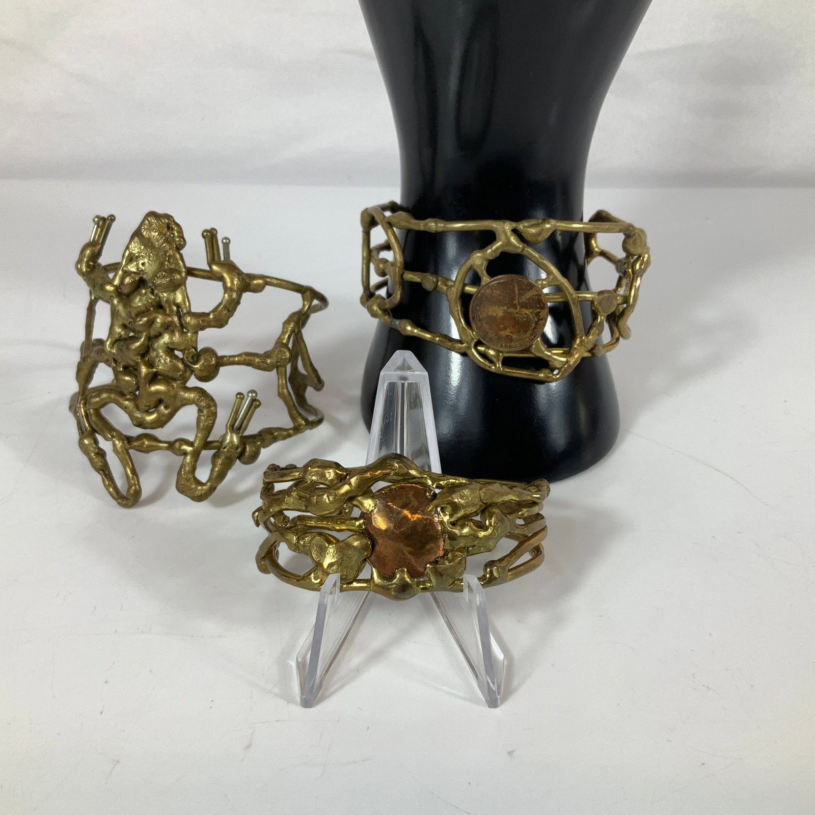 3pc Brutalist Style Studio Art Brass and Copper Coin Cuff Bracelets: A trio of handcrafted modernist cuff bracelets featuring an organic, Brutalist aesthetic with a textured, melted metal finish. The collection includes one large openwork cuff adorned with a stylized