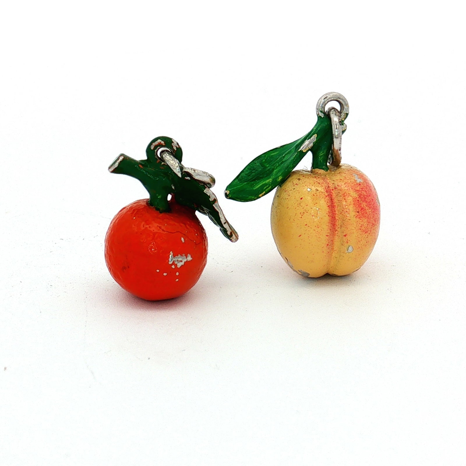 2pc Enamel Fruit Charms: A set of enameled metal charms depicting an orange and a peach. Dimensions: 0.5"L x 0.75"H Weight: 10.65 g