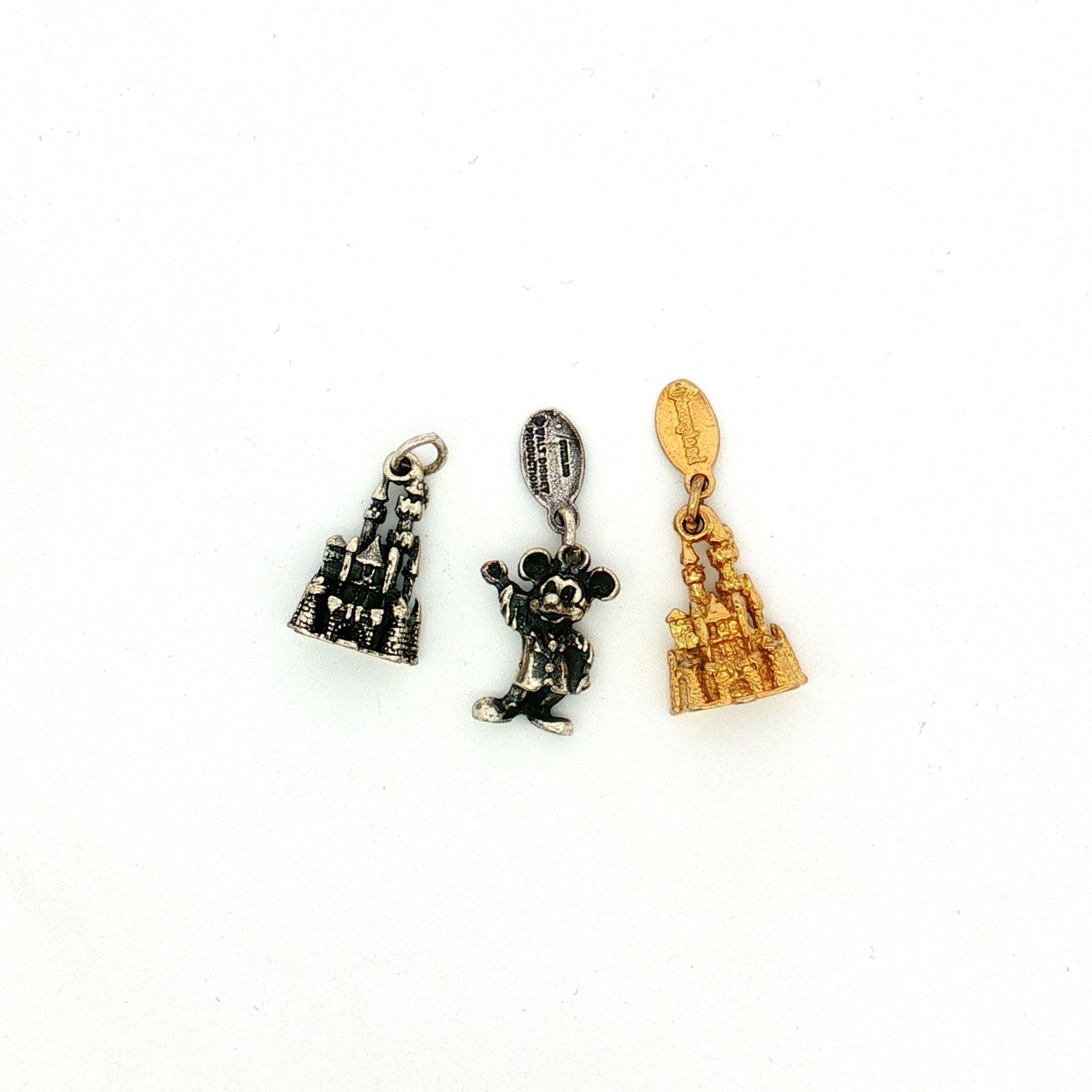 3pc Sterling Silver and Gold-Plated Disneyland Charms: A group of sterling silver charms, including a Mickey Mouse charm and two modeled after the Sleeping Beauty castle, one of which features gold-plating. Each charm is marked Disneyland and Sterling. Di