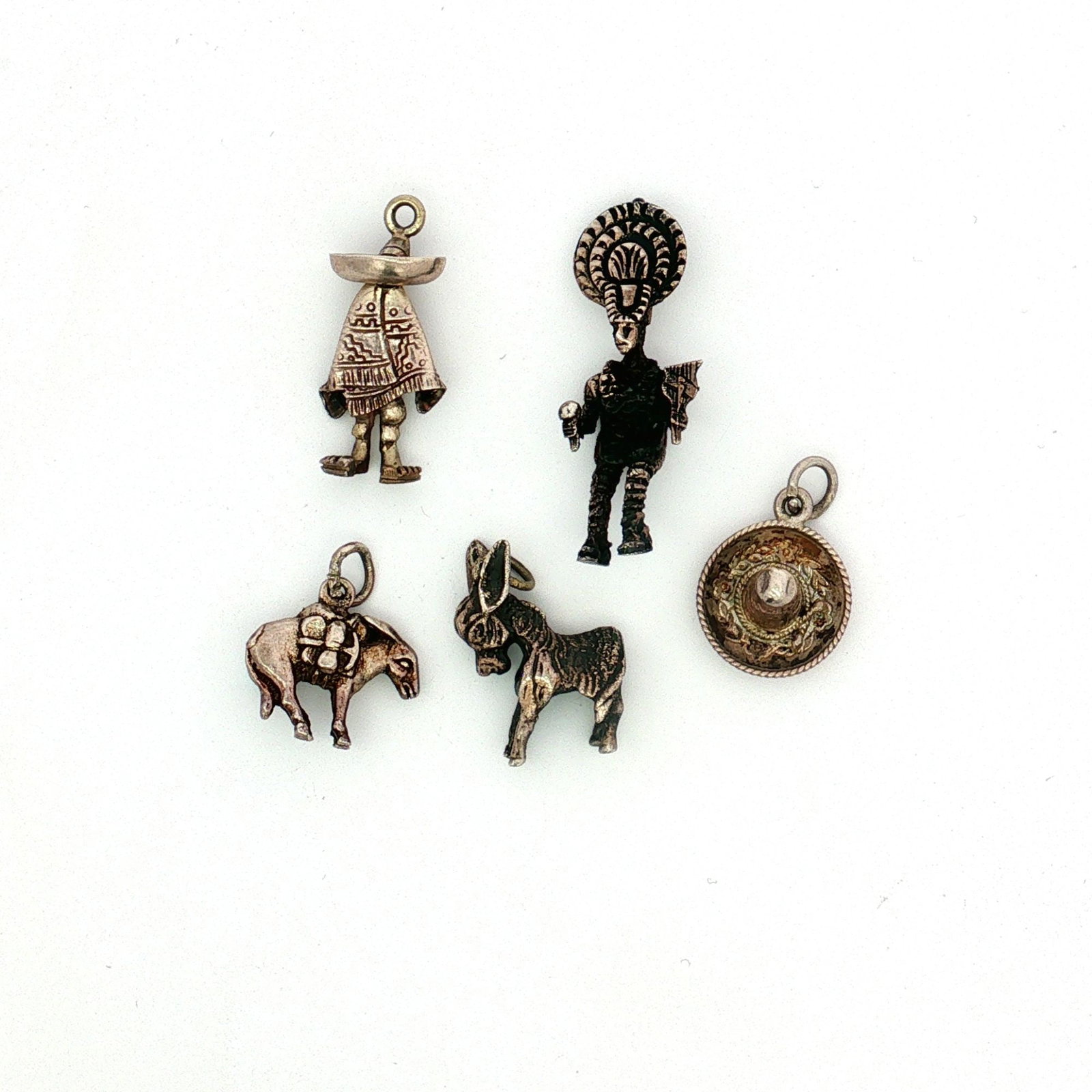 5pc Sterling Silver Miniature Mexican-Themed Charms: A collection of sterling silver charms inspired by Mexican culture, including two donkeys, a figure wearing a sombrero and shawl, a sombrero marked Mexico, and a Mayan-inspired figure wearing a headdr