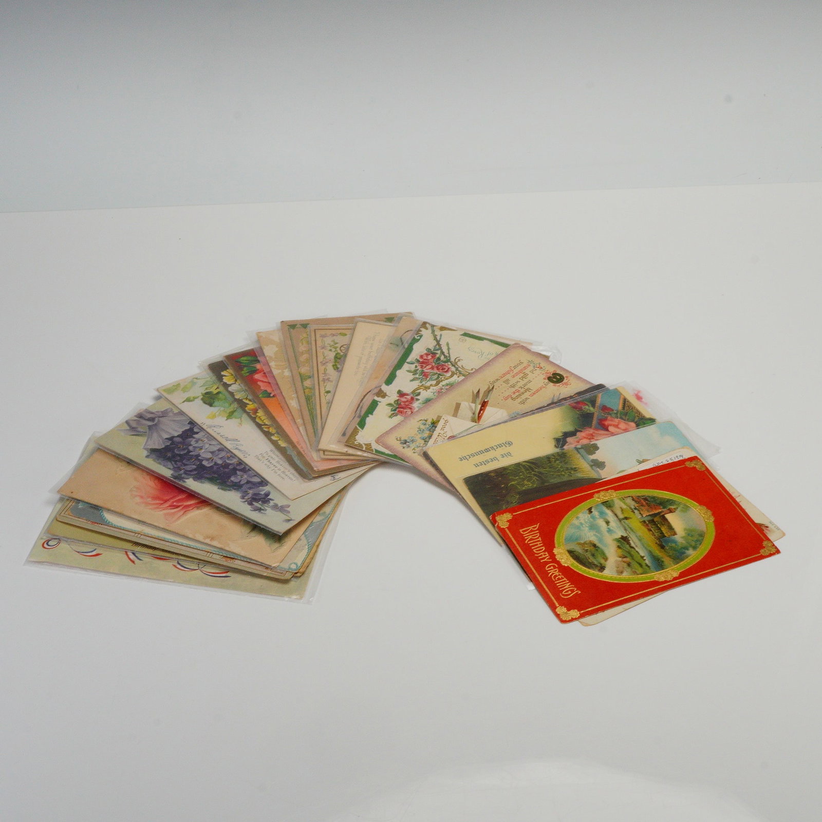 23pc Floral and Illustrated Collectible Postcards: A collection of various post cards including Happy Birthday, Greetings, and German designed with floral motifs, decorative illustrations, and pastoral imagery. The group includes both used and unused 