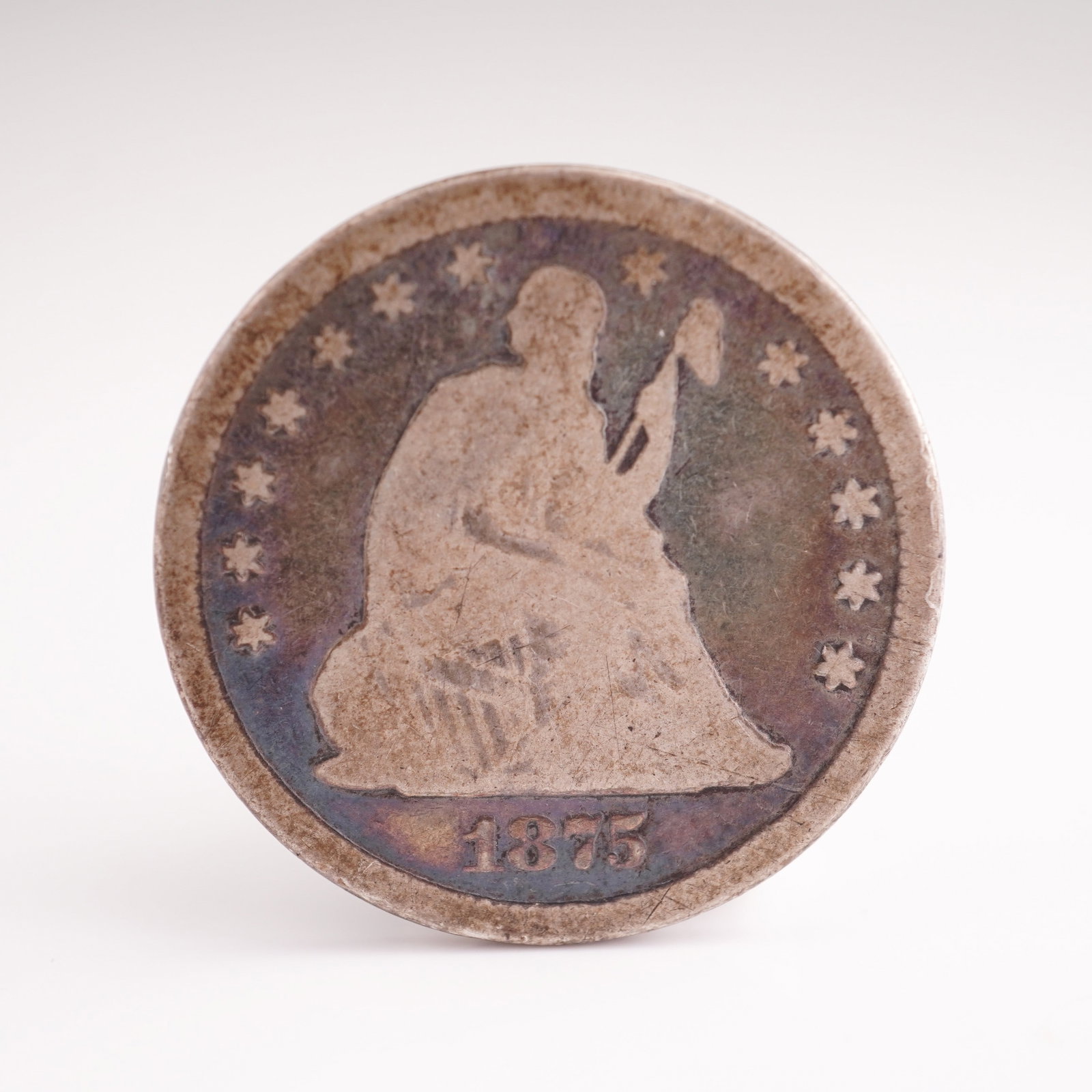 1875 U.S. Silver Liberty Seated Quarter Coin: The obverse features Seated Liberty facing right over her shoulder, holding a cap on a pole and a shield, surrounded by 13 stars. The reverse shows an eagle clutching arrows and an olive branch in its