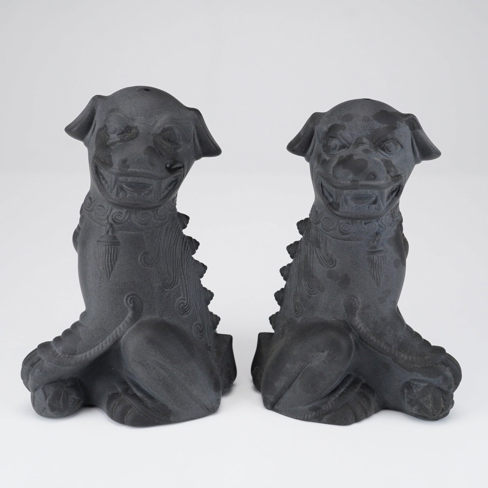 Pair of Wedgwood Black Basalt Foo Dog Salt and Pepper Shakers: This pair of salt and pepper shakers is manufactured by Wedgwood in black basalt, a fine-grained, unglazed matte black stoneware. The shakers are modeled in the form of seated foo dogs, also known as 