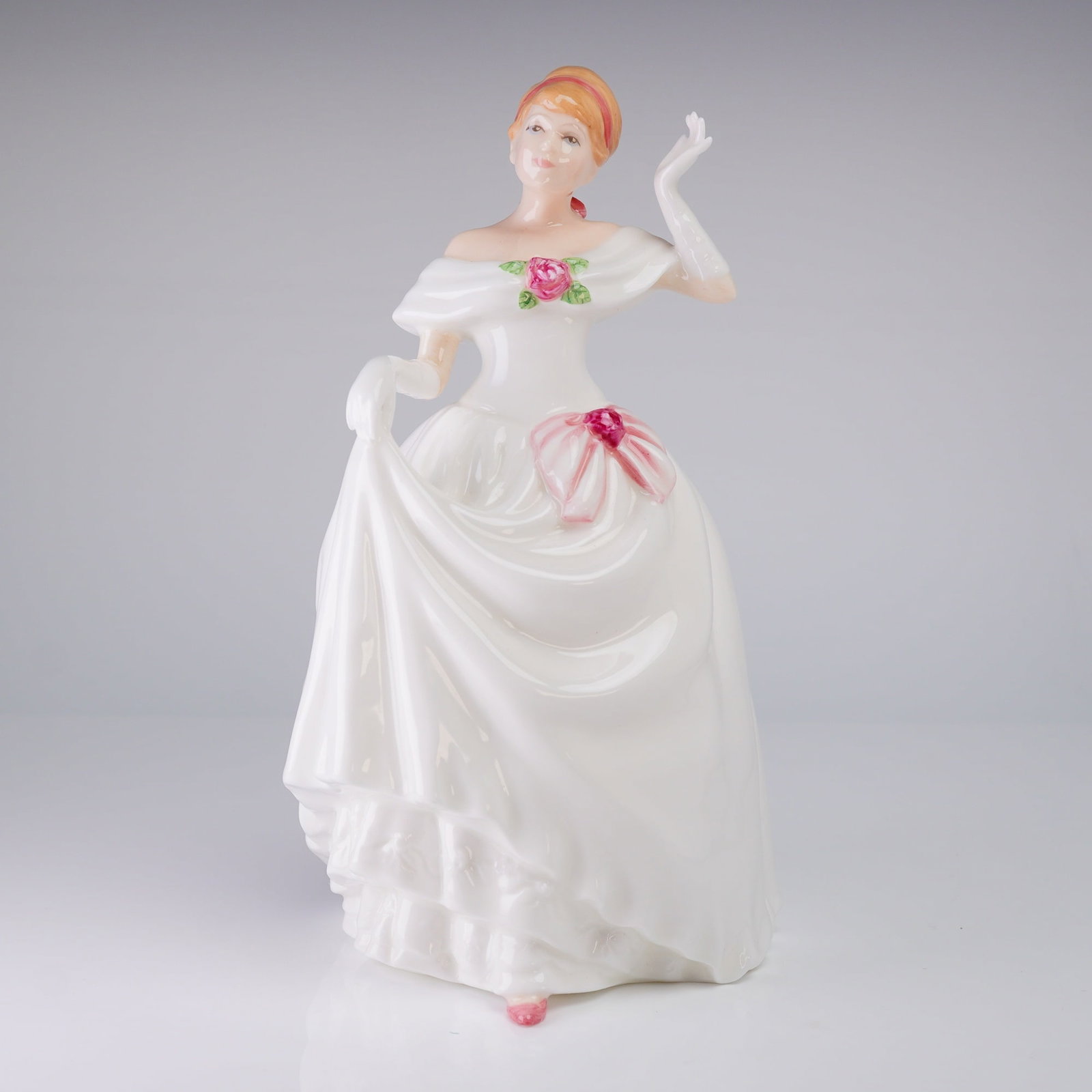 Royal Doulton Figurine Dawn HN3600: A glazed bone china figurine by Royal Doulton model HN 3600, titled "Dawn." The figure depicts a lady in a full-length, off-the-shoulder white ballgown. The figure has reddish-blonde upswept hair. The