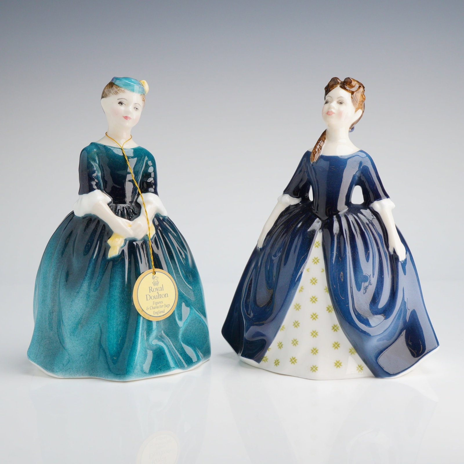 2pc Royal Doulton Figurines, Cherie HN2341 and Debbie HN2385: Two Royal Doulton figurines, including CHERIE (1965, teal gown) and DEBBIE ( 1969, deep blue gown), both bearing original hang tags, marked on base with Royal Doulton backstamp. Dimensions: 6.00"H Wei