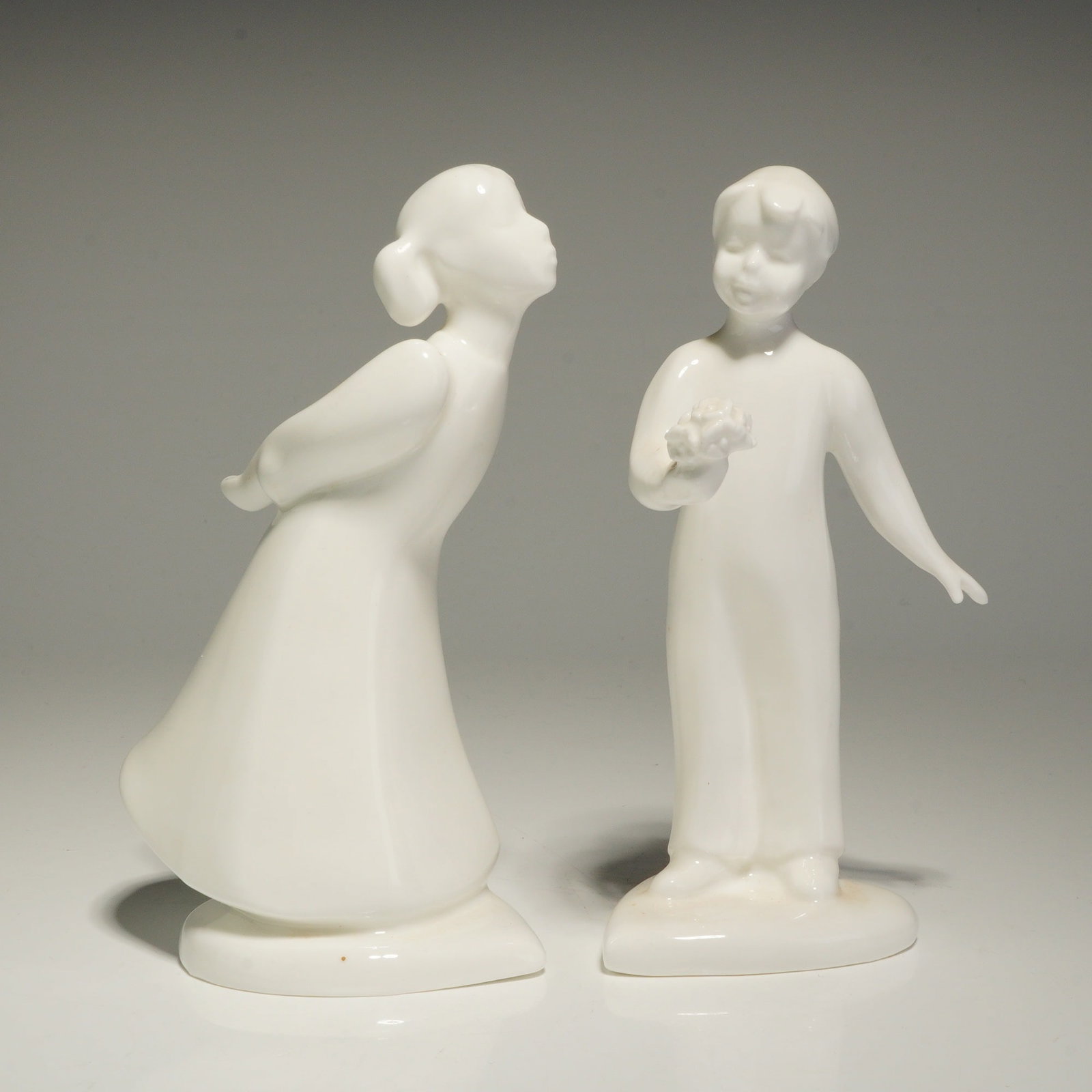 2pc Royal Doulton Figurines, The Kiss Girl HN4065 and Sweetheart Boy HN4351: A pair of Royal Doulton porcelain figurines from the Images collection, featuring stylized, minimalist forms in a monochromatic white glaze. This 2pc Royal Doulton figurines set includes The Kiss Girl