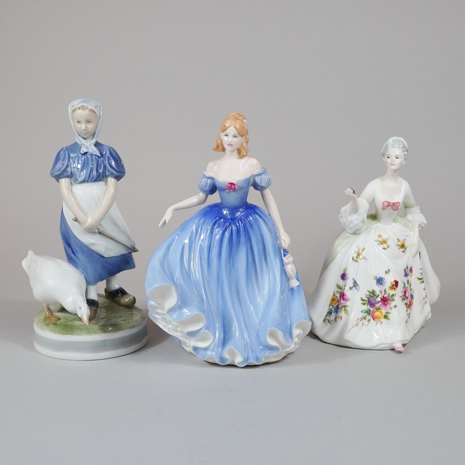 3pc Royal Doulton and Royal Copenhagen Porcelain Figurines including Melissa HN3977 and Diana HN2468: This lot features three glazed porcelain figurines produced by Royal Doulton and Royal Copenhagen. The first figurine is a Royal Copenhagen piece titled Girl with Goose (Number 527), depicting a girl 