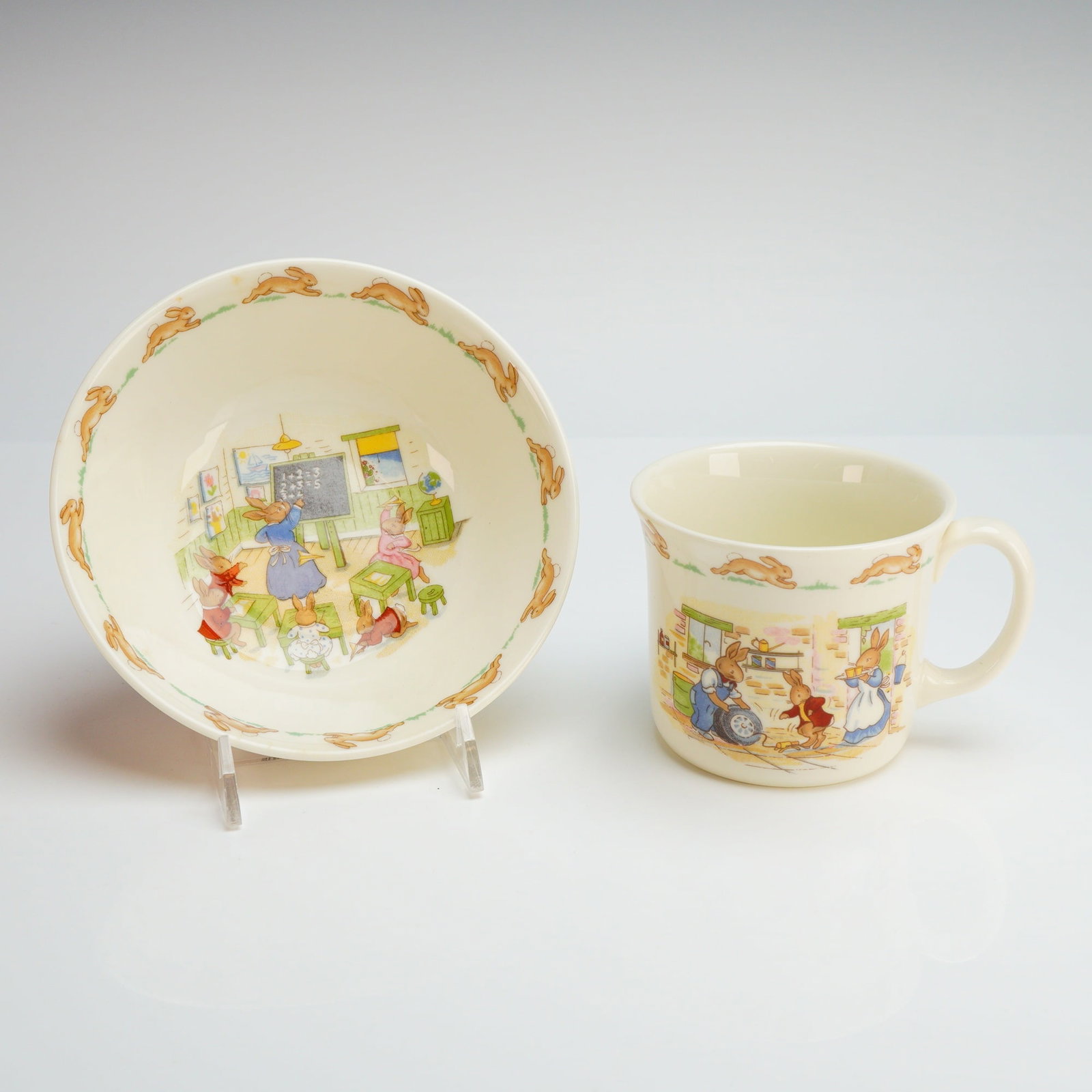 A 2 Piece Royal Doulton Bunnykins Albion Shape Infant Set: This 2 piece infant set is manufactured by Royal Doulton in the Bunnykins pattern and features the Albion shape. The set is composed of bone china and includes a bowl and a single-handled mug. The bow