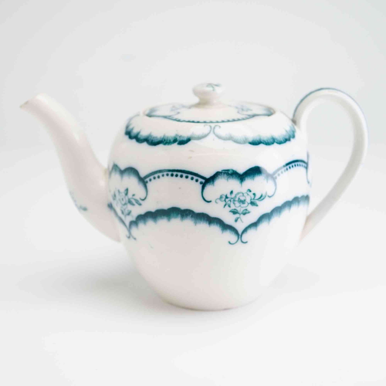 Wedgwood Earthenware Mini Teapot with Blue Floral Decoration: A Wedgwood earthenware mini teapot featuring a globular body decorated with transfer-printed floral patterns in a deep teal blue-green color. The design is organized into three horizontal registers of