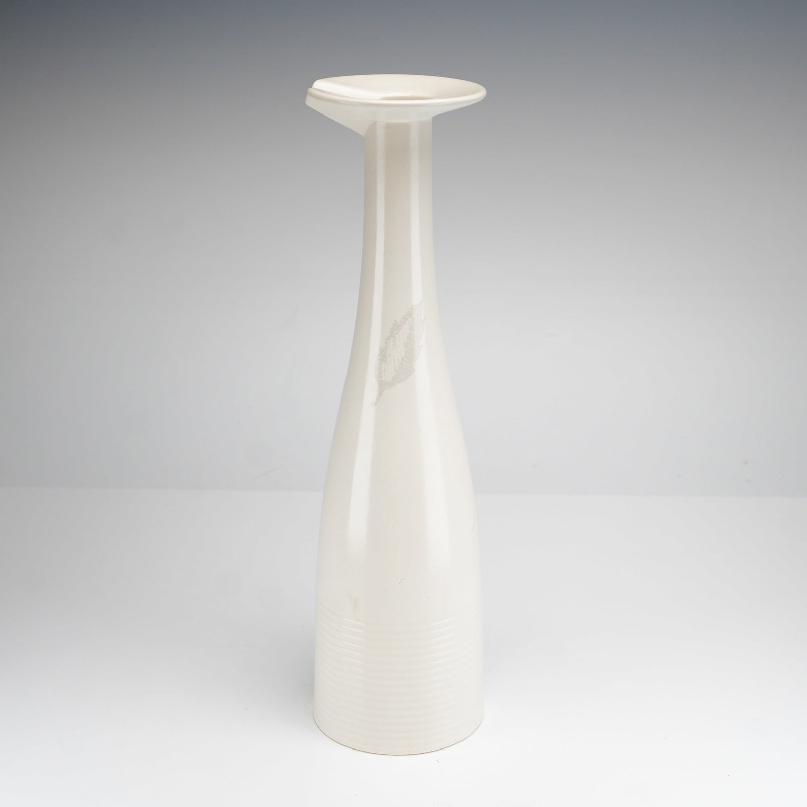 Paul Costelloe for Wedgwood Ceramic Oil Bottle, 1999: A contemporary cream-colored ceramic oil bottle designed by Paul Costelloe for Wedgwood. The vessel features a tall, slender, tapering form rising from a circular base decorated with horizontal ribbed