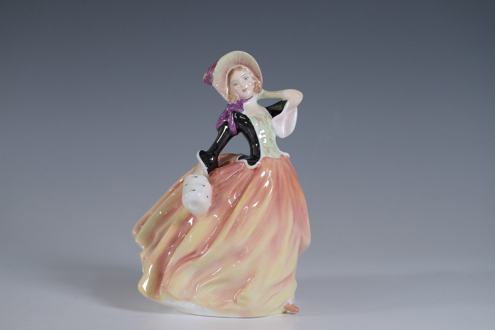 Royal Doulton Figurine, Autumn Breeze HN2131: Royal Doulton figurine titled Autumn Breeze, model HN2131. This elegant hand-painted porcelain figure depicts a graceful woman in a flowing pastel gown with a bonnet, capturing the charm of a breezy a