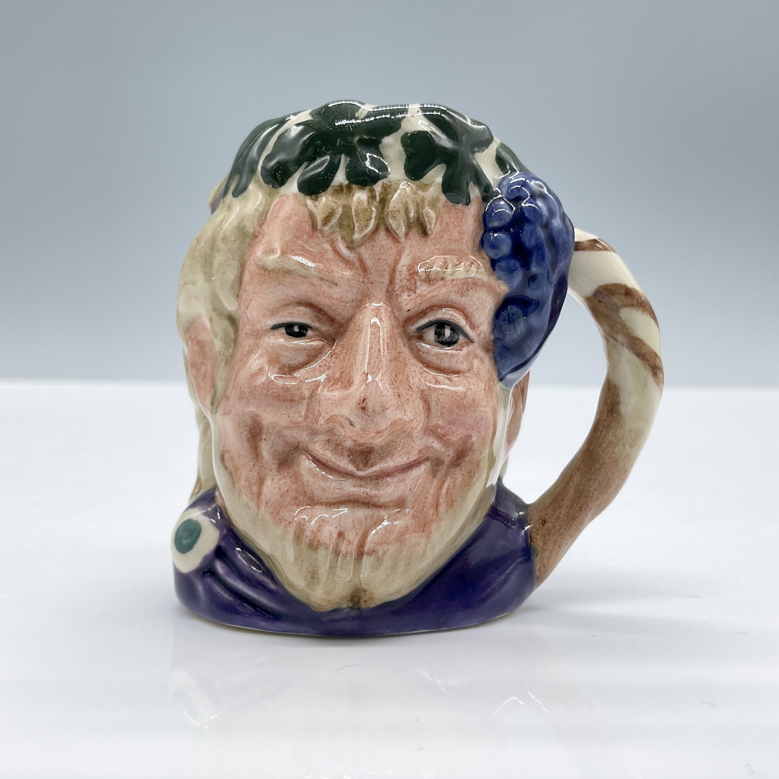 Bacchus D6521 - Mini - Royal Doulton Character Jug: Maroon robes; green leaves and purple grapes adorn the head. Royal Doulton backstamp. Artist: Max Henk Dimensions: 2.75"L x 2"W x 2.5"H Date or Era: 1960 - 1991 Manufacturer or Brand: Royal Doulton <