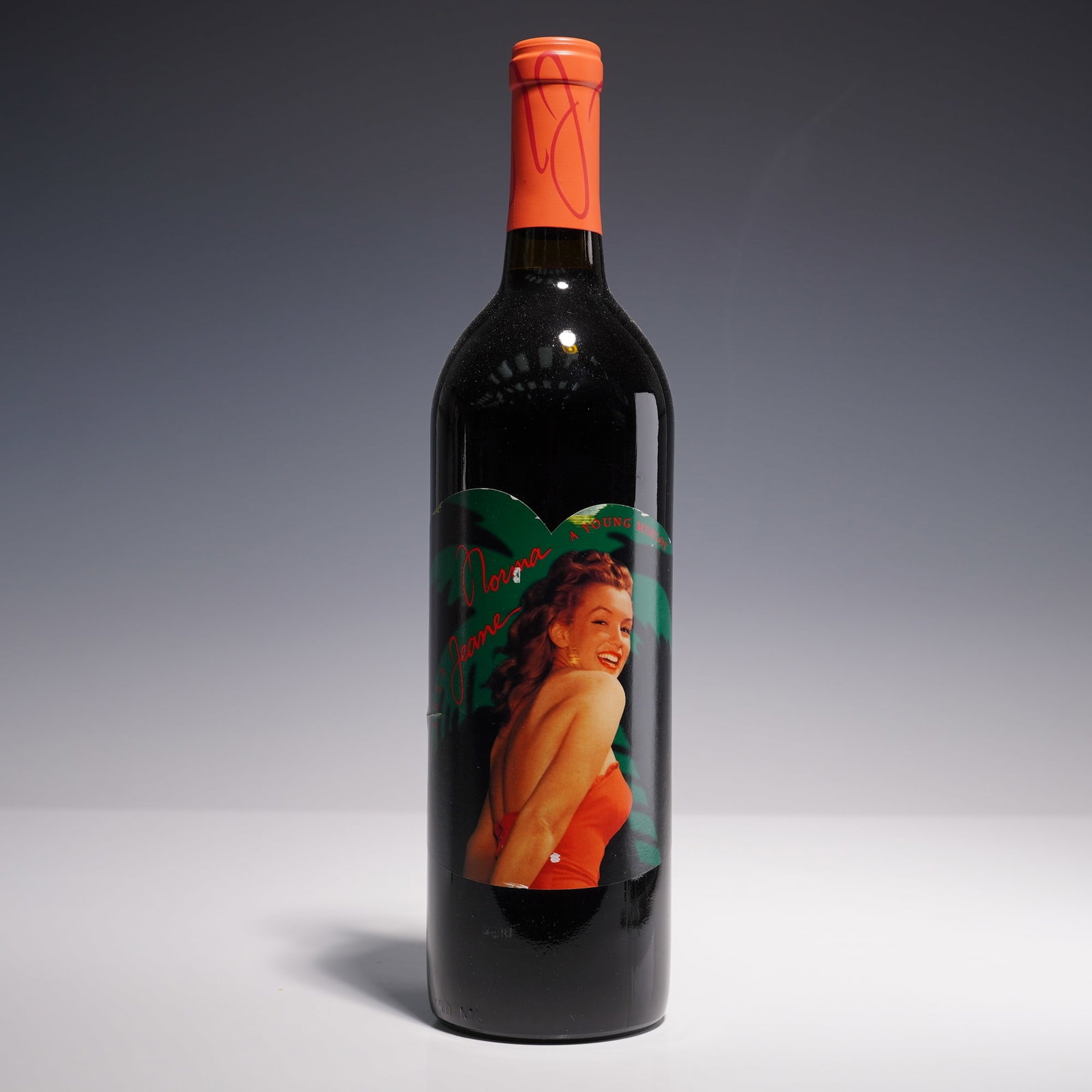 2002 Norma Jeane California Red Wine, Bottle of Young Merlot, Fifth Vintage: A collectible Fifth Vintage 750ml bottle of 2002 Norma Jeane California red wine. The front label features a young Marilyn Monroe in a vibrant tropical-themed portrait wearing a bright orange halter d