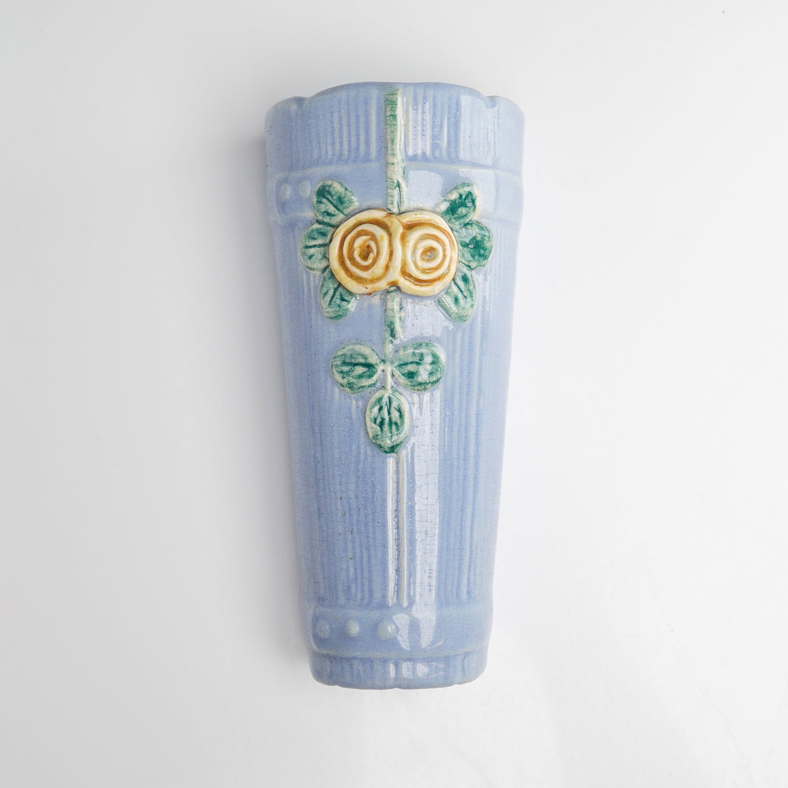 Weller Pottery Roma Wall Pocket: A Weller Pottery glazed earthenware wall pocket produced in the Roma pattern. The tapered form features a relief-molded floral motif consisting of two stylized yellow roses and green foliage set again