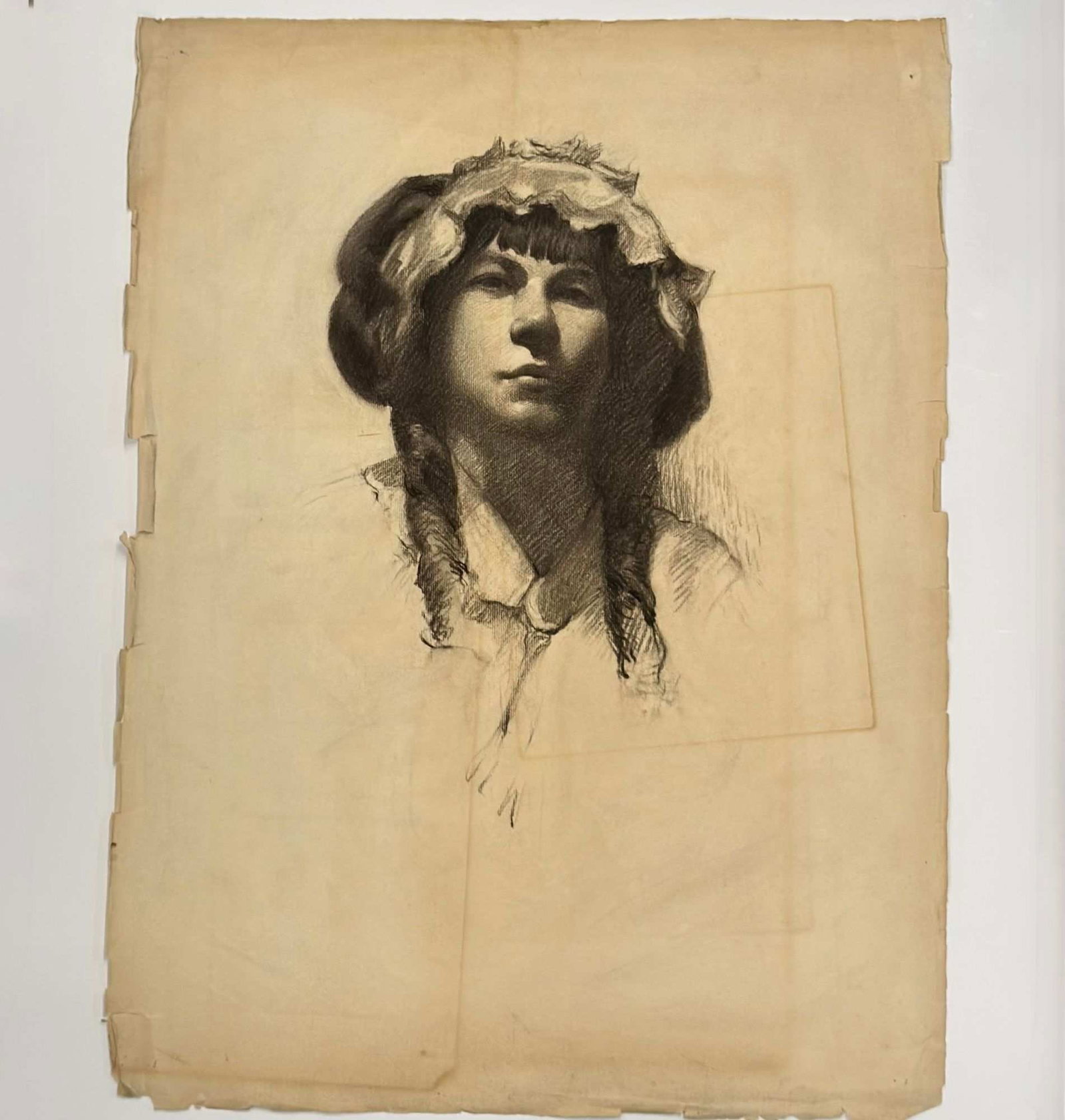 Angelo Comolli, Portrait of a Young Woman in a Bonnet, Charcoal on Paper, ca. 1911-1913: This original charcoal drawing on toned wove paper is by Angelo Comolli (Italian, 1863-1949), identified as being from his portfolio created while at the Eric Pape School of Art in Boston, circa 1911-
