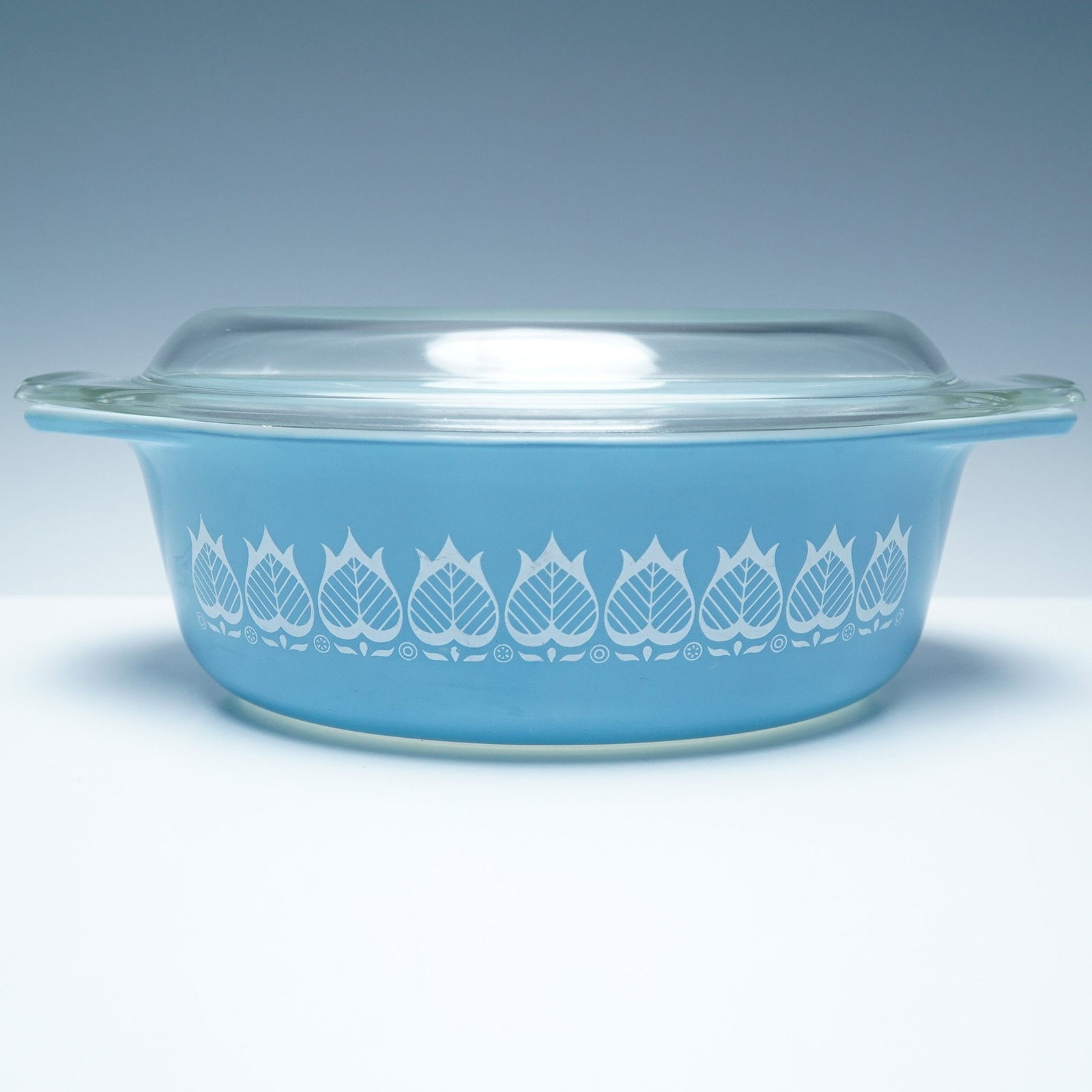 Vintage Pyrex Blue Tulip 1.5 Qt. Casserole Dish with Lid: A vintage Pyrex Blue Tulip 1.5-quart casserole dish with its original clear glass lid. This sought-after mid-century design features a sky-blue exterior adorned with a white tulip motif, a hallmark of