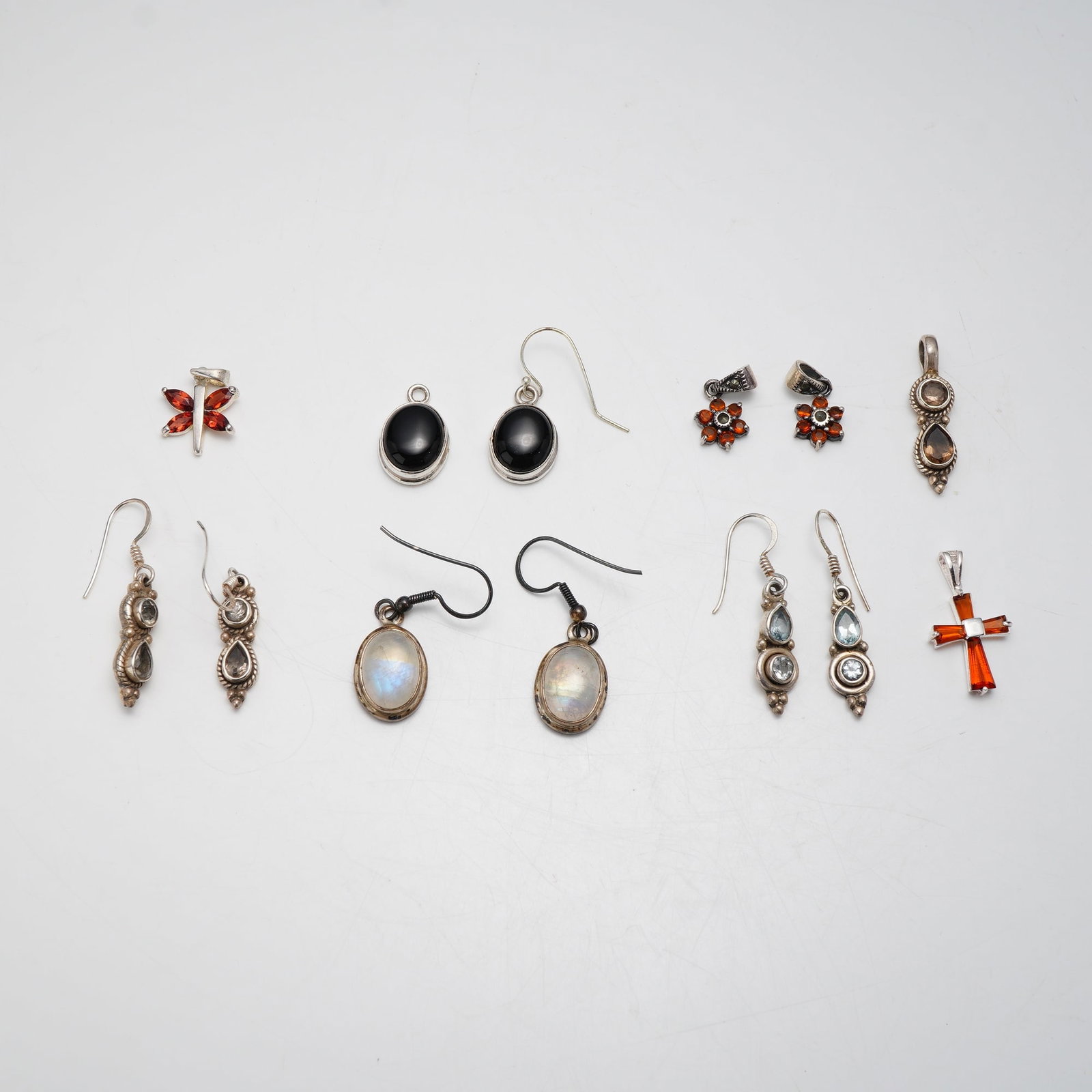 13-Piece Collection of Sterling Silver and Multi-Gemstone Jewelry: This collection consists of 13 pieces of sterling silver jewelry featuring an assortment of gemstones. The group includes four pairs of drop earrings and five individual pendants. The items are constr