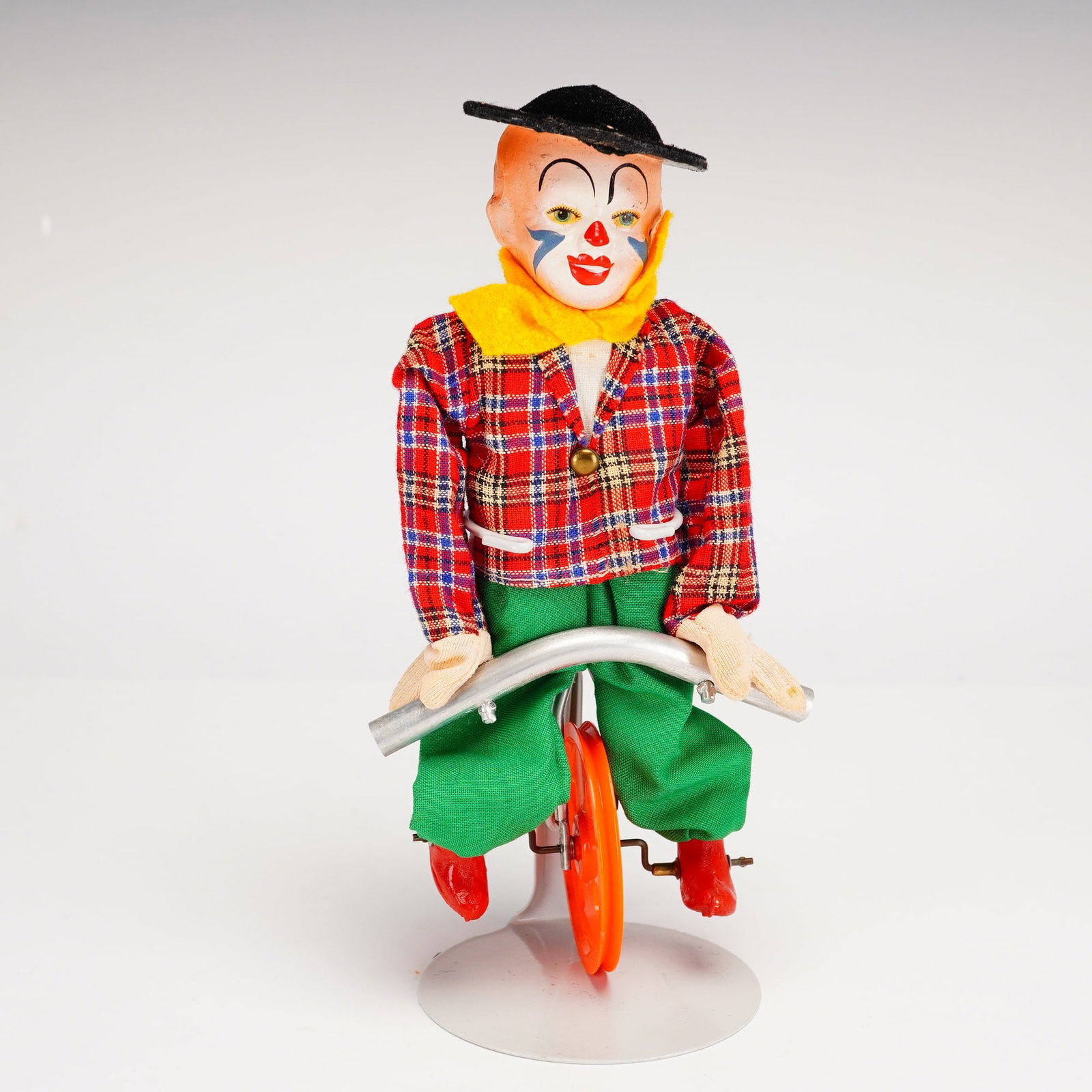 FEWO Tightrope Balancing Clown Unicycle Toy, 1950s: FEWO West German mechanical tightrope balancing clown toy, circa 1950s. This gravity-balanced unicycle toy features a figure with a painted composition head, black felt hat, and a vibrant fabric outfi