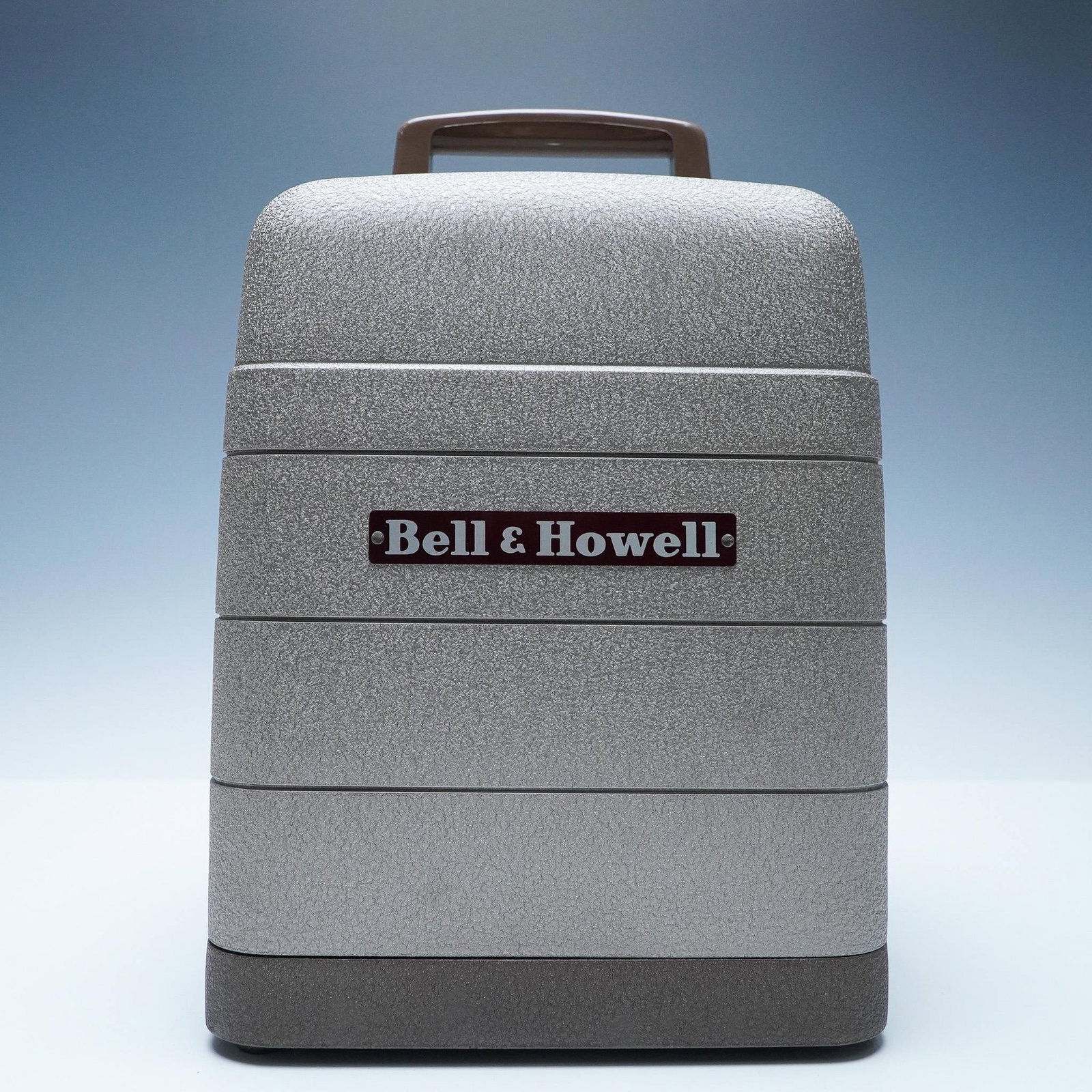 Bell & Howell 16mm Film Projector with Original Box: A vintage Bell & Howell 16mm film projector, showcasing the brand's renowned durability and craftsmanship. This classic model features a sleek metal housing with a textured finish, built for reliabili