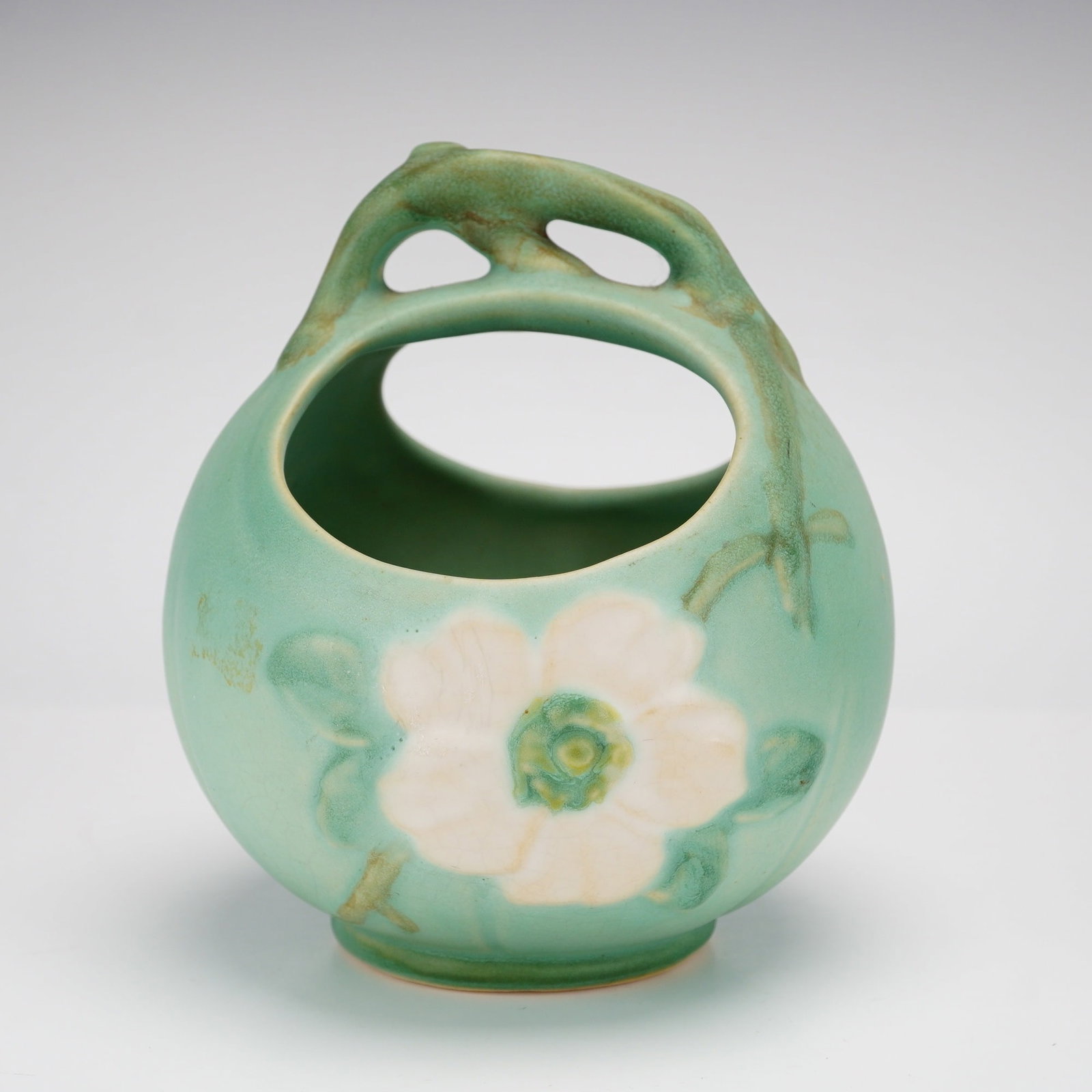 Weller Wild Rose Basket Planter: This Weller Wild Rose Basket Planter is a piece of earthenware art pottery produced by Weller Pottery. The item features the Wild Rose pattern, characterized by a molded relief design of a large white
