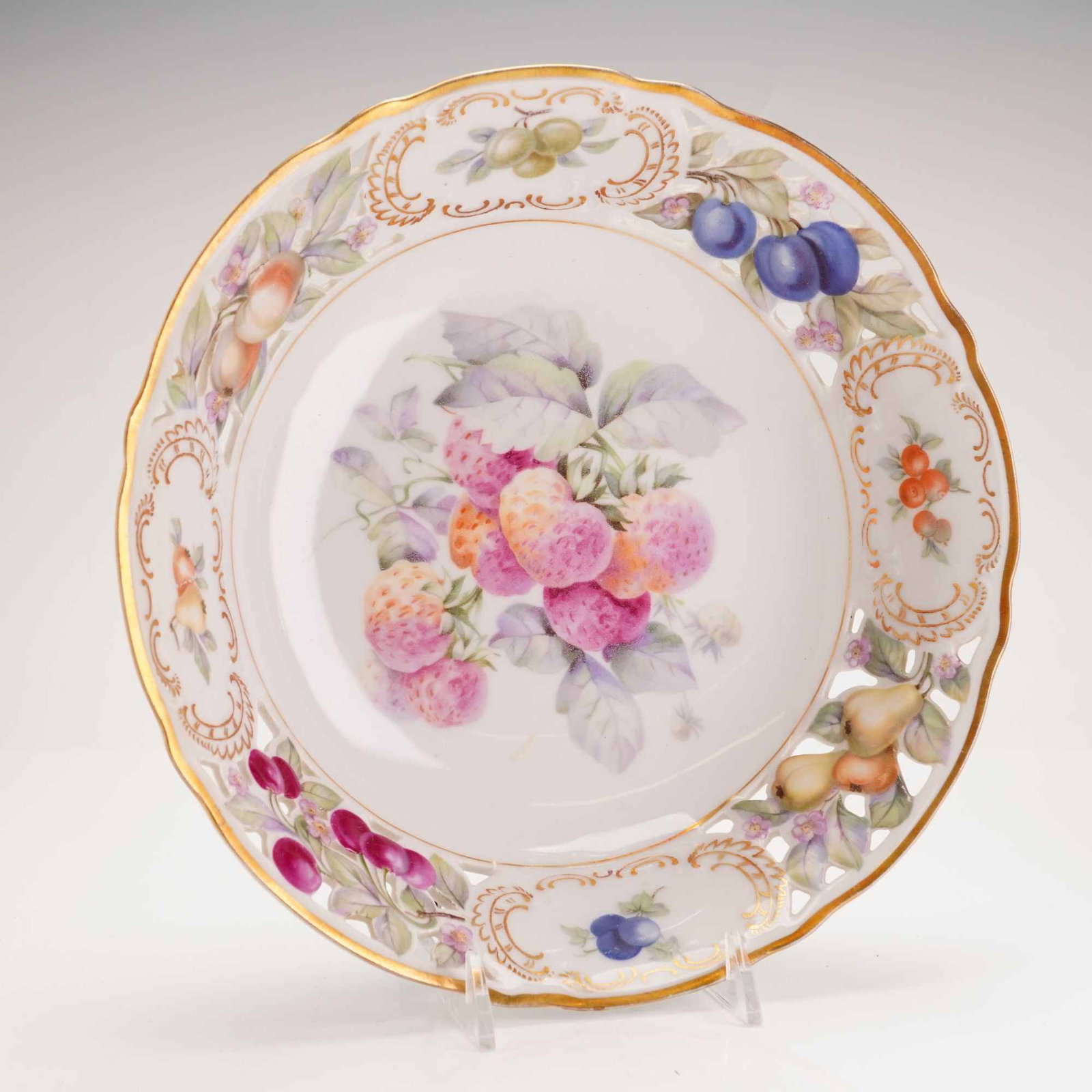 Schumann Bavaria Reticulated Porcelain Fruit Bowl: Vintage piece characterized by its pierced lattice edge and hand painted fruit motif. Light pastel colors used in design along with raised fruit design along rim. Likely produced 1930 to 1950 period. 