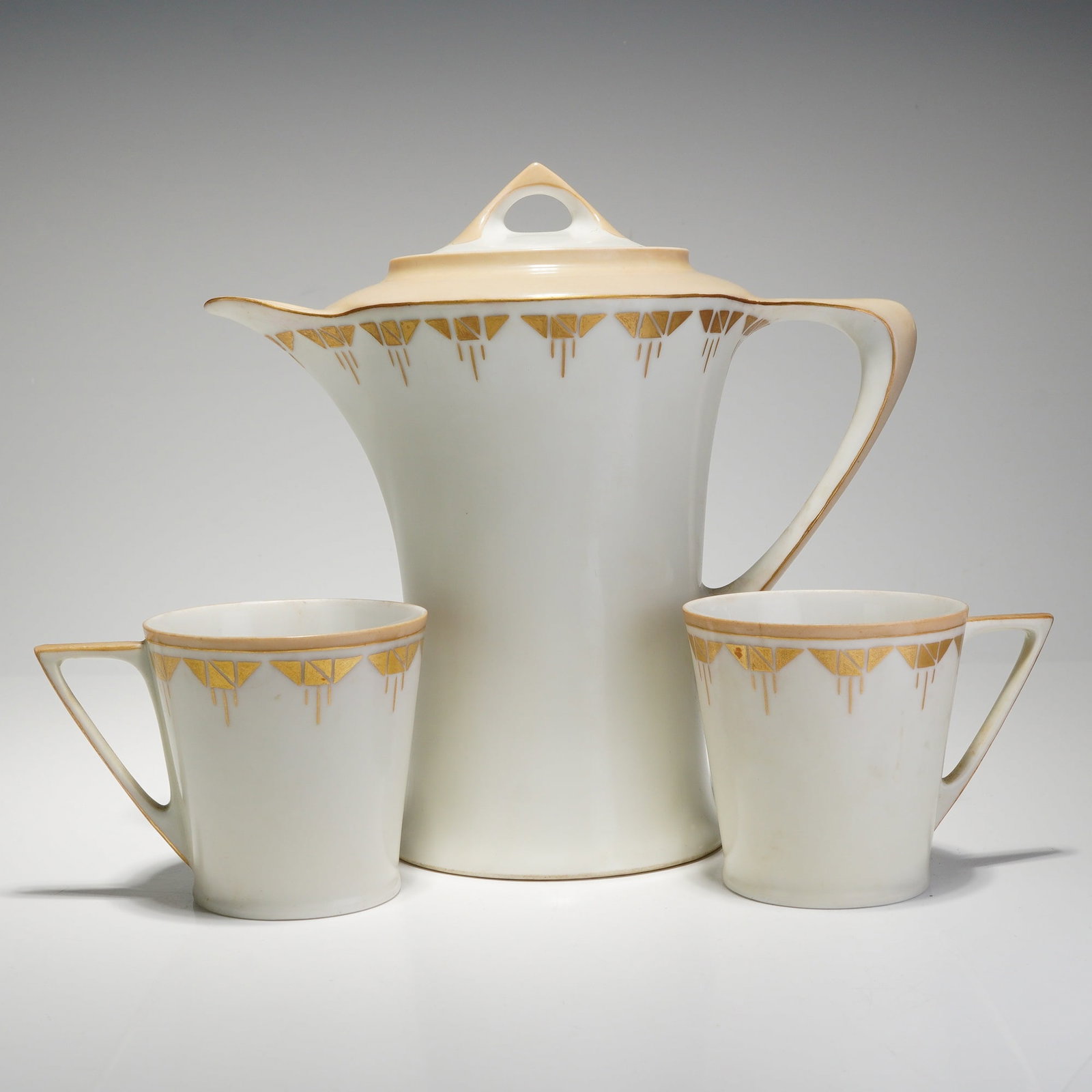 Hutschenreuther Art Deco Porcelain Chocolate Pot and Two Cups: This three-piece Hutschenreuther Bavaria porcelain chocolate service is designed in the Art Deco style, dating to circa 1920??"1930. The set consists of a tall, lidded chocolate pot and two matching c