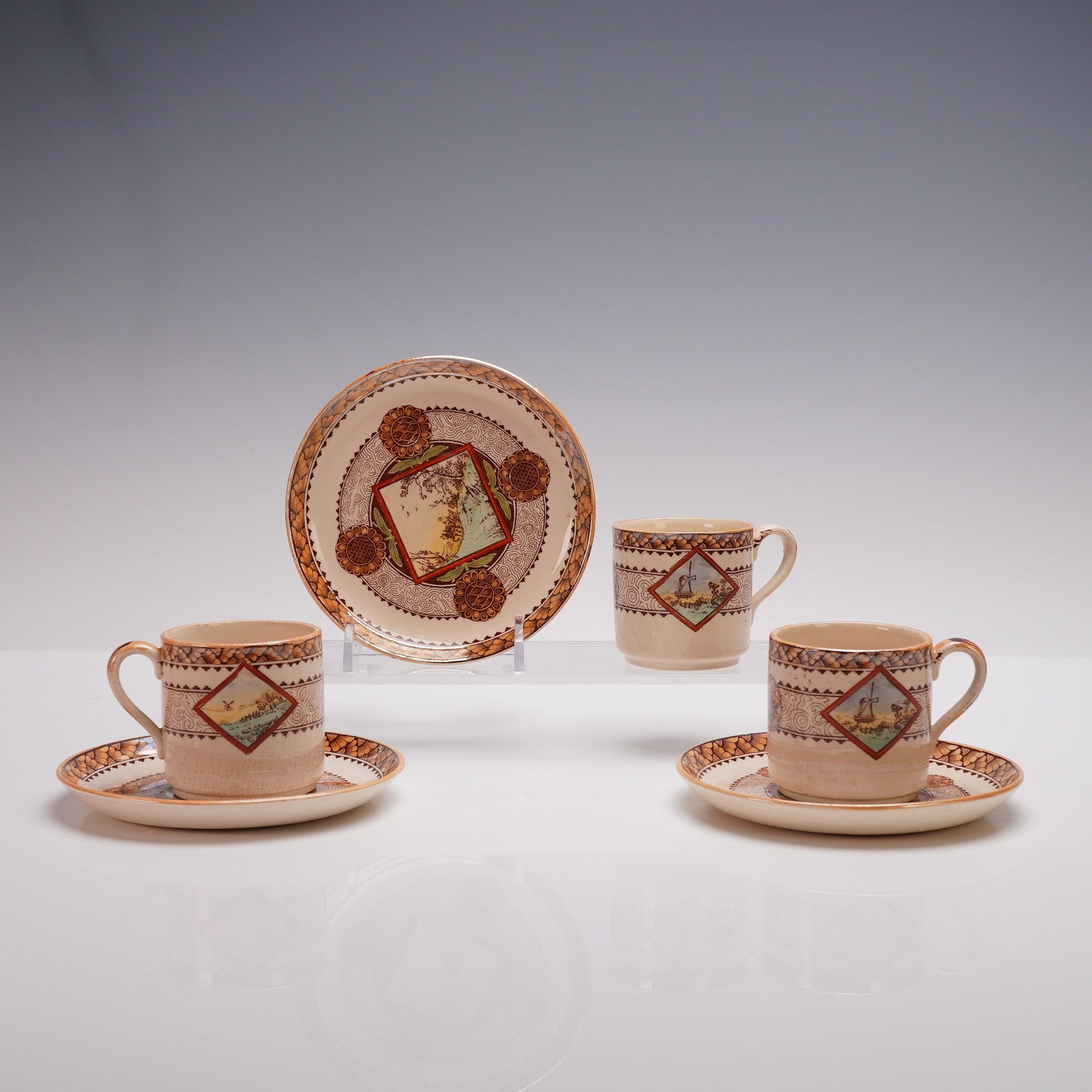 6pc Brownfield & Sons Wisconsin Demitasse Cup & Saucer Set: This finely crafted ceramic set includes three demitasse cups and three matching saucers, each decorated with transferware designs in warm tones of brown, orange, and green. The cups feature scenic la