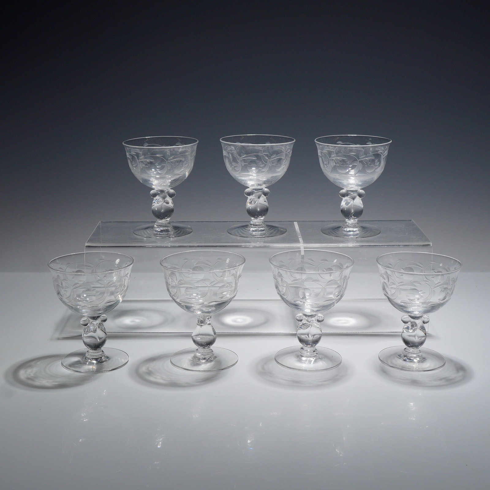 Set of Seven Heisey Southwind Pattern Crystal Sherbet Glasses: This set of seven glasses is attributed to Heisey, featuring the Southwind wheel-etched pattern (etching number 1030) on the Barcelona stem (stem number 1506). The collection consists of seven matchin