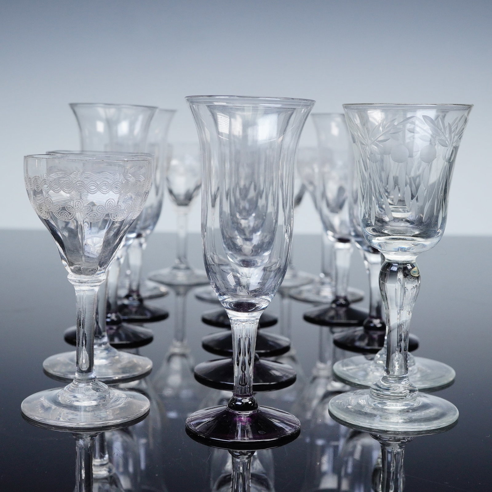 17pc Etched and Cut Cordial Stemware Glasses: A diverse assemblage of seventeen vintage pieces of stemware comprising an assortment of etched and cut glass goblets and wine glasses in varying forms and motifs. Includes eight short stemmed glasses