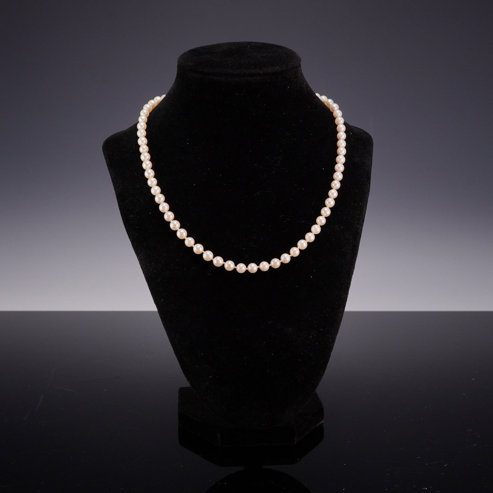 Costume Jewelry White Pearl Style Necklace with Filigree Clasp: A single-strand costume jewelry necklace composed of small, uniform white pearl-style beads. The necklace is constructed with individual hand-knots on a light-colored cord. The beads exhibit a creamy-