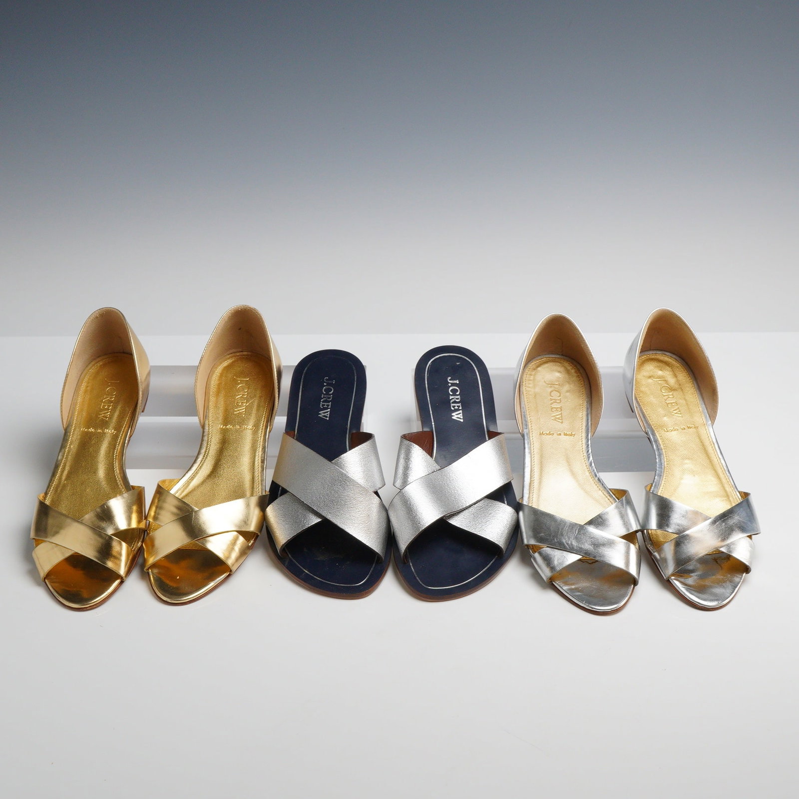 Three Pairs J.Crew Metallic D'Orsay Flats and Slide Sandals: This lot features three pairs of J.Crew women's metallic leather sandals in sizes 5 and 5.5. The collection includes one pair of gold metallic Cristobal D'Orsay-style flats featuring a cross-over toe 