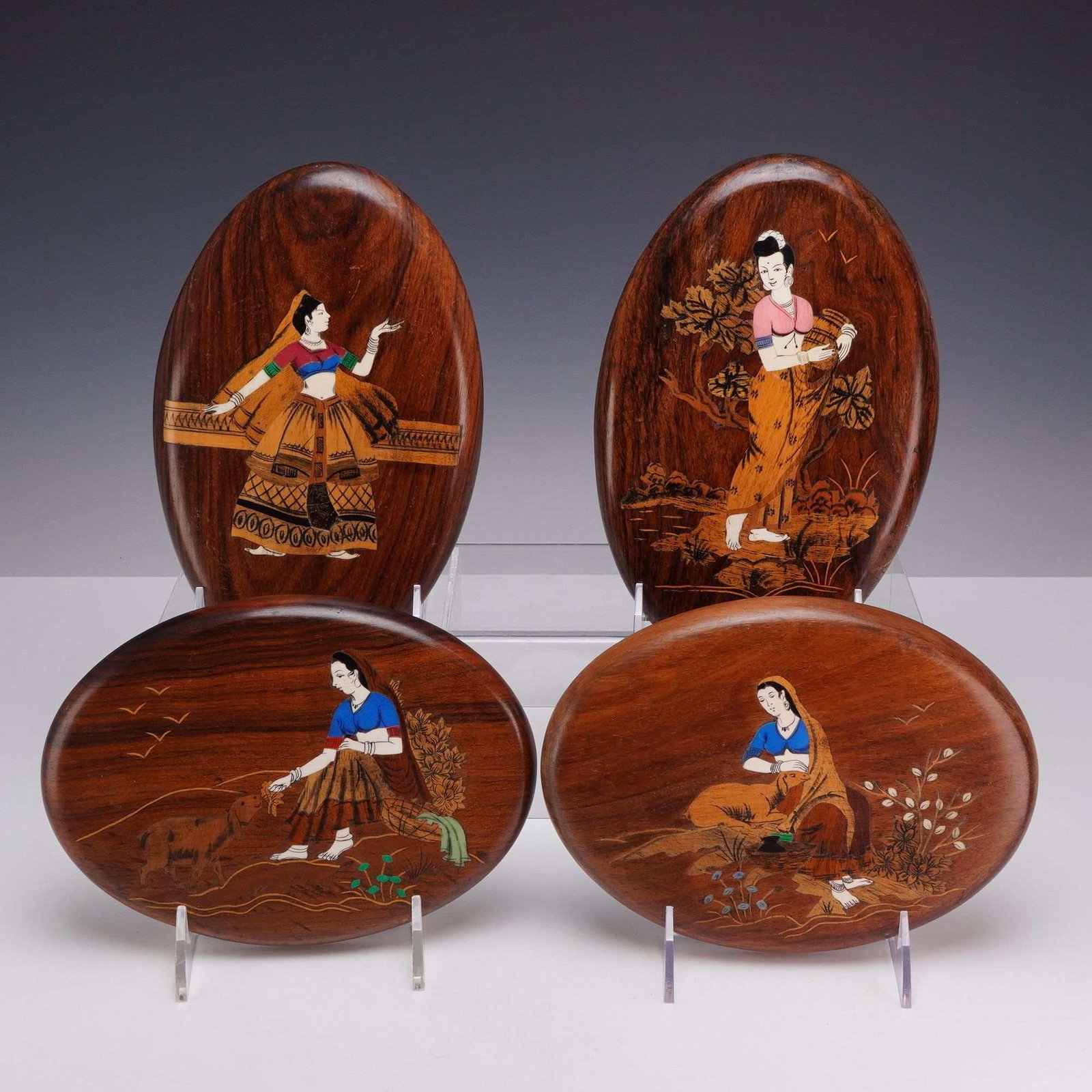 Set of 4 Vintage Indian Wood and Bone Marquetry Inlay Small Oval Plaques: A set of four small oval decorative wall plaques featuring inlaid marquetry scenes of Indian women in traditional attire. Each plaque is constructed from a dark, figured hardwood ground, likely rosewo