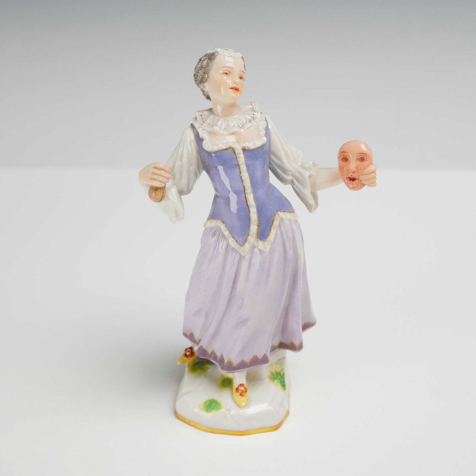Meissen Porcelain Female Theater Peformer Figurine: This porcelain figurine depicts a female theater performer in 18th century-style clothing, holding a mask and clapper. The underside features the Meissen backstamp, and is impressed with numbers 1118 