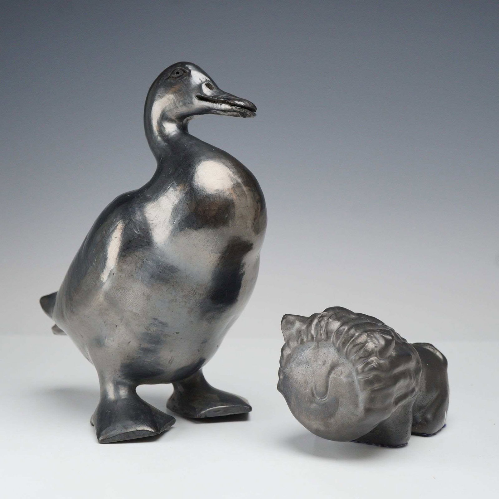 2pc Modernist Burnished Blackware Pottery Animal Figurines, Duck and Lion: A lot of two black pottery animals, comprising one standing duck and one reclining lion, crafted in the tradition of burnished blackware pottery. These pieces feature a deep black color and a high-glo