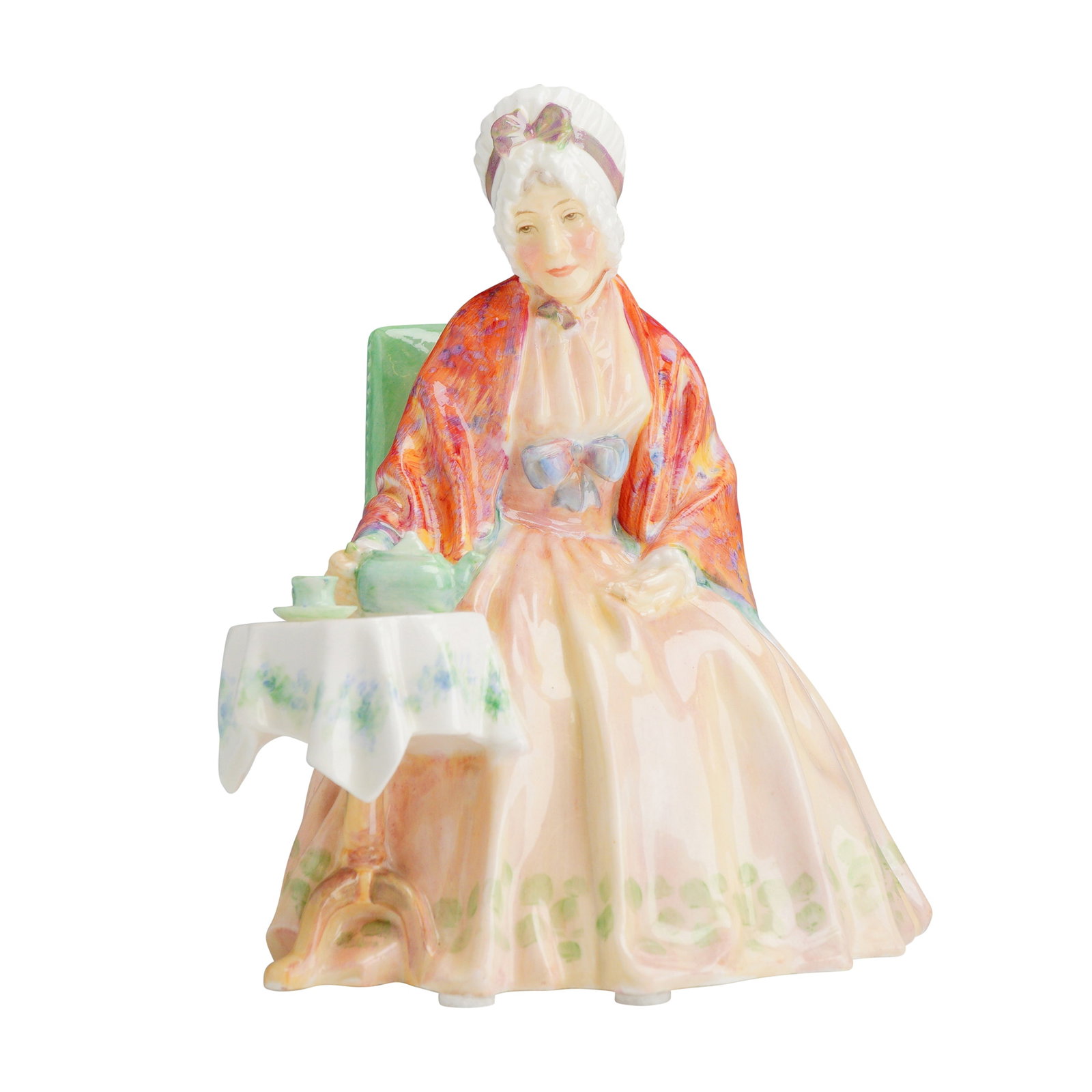Royal Doulton Porcelain Figurine Granny HN 1832: A Royal Doulton glazed porcelain figurine titled Granny, model number HN 1832. The figure depicts an elderly woman seated in a high-backed green chair at a three-legged table. She is shown holding a t