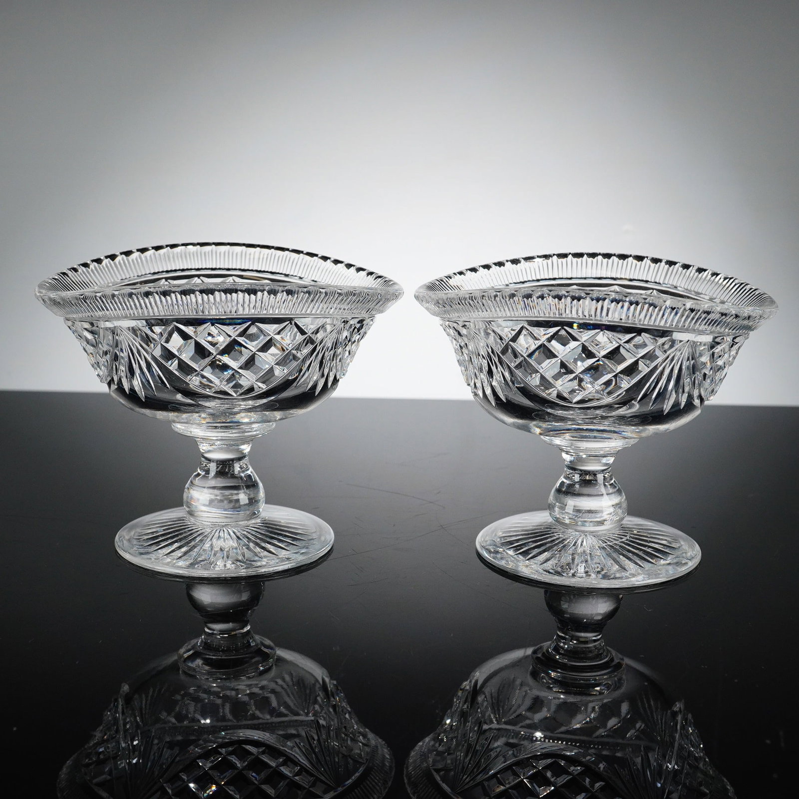 Pair of Cut Crystal Footed Sherbet Dishes: This pair of crystal serving footed sherbet dishes is crafted in the American Brilliant Period style from heavy lead crystal. Each boat-shaped dish features a flared, oval rim with a fine notched or s