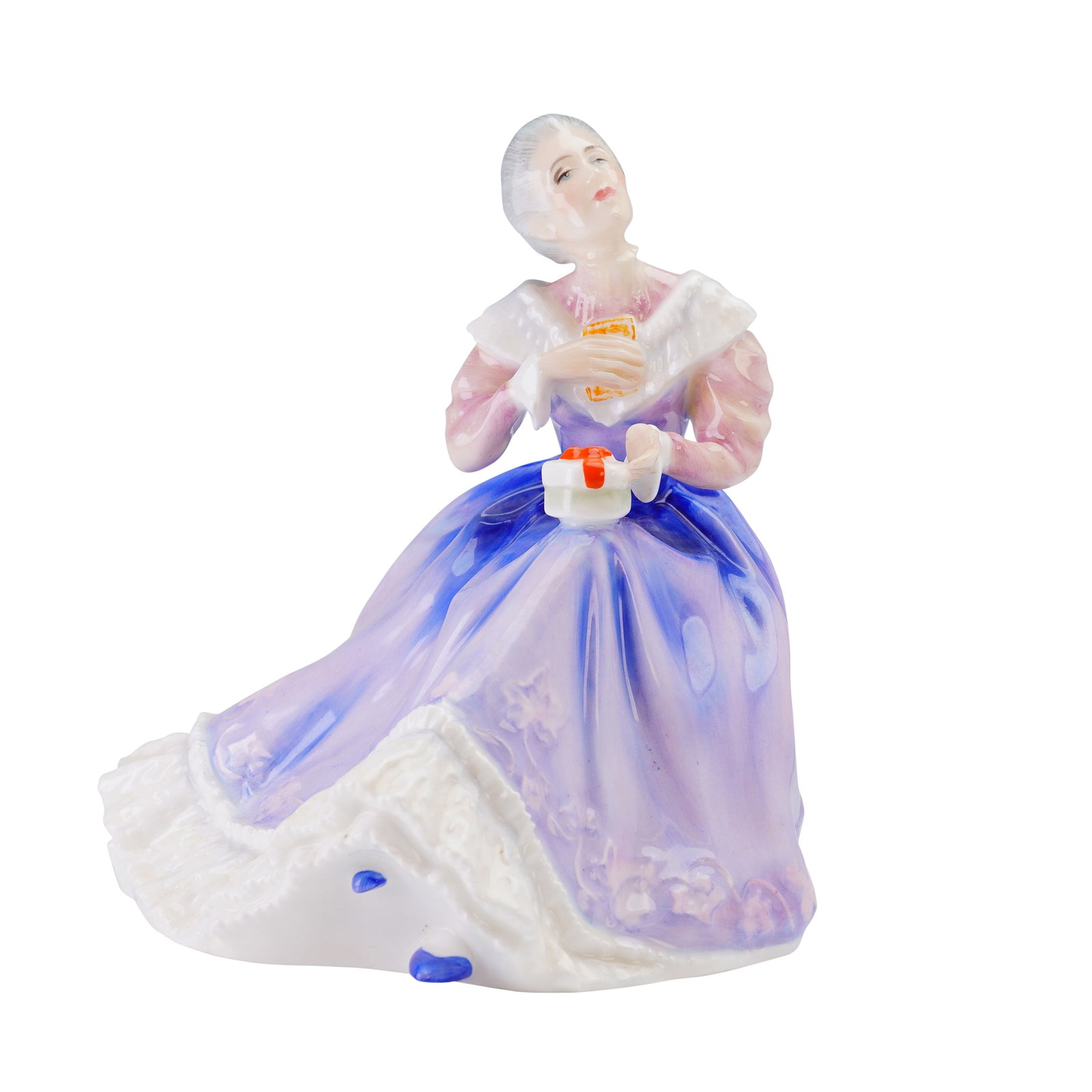 Royal Doulton Figurine, Happy Anniversary HN3097: The piece depicts a woman with upswept gray hair, seated on a green-topped stool and looking upward while holding a small white gift box with a red ribbon. She is dressed in a full-length, flowing lav
