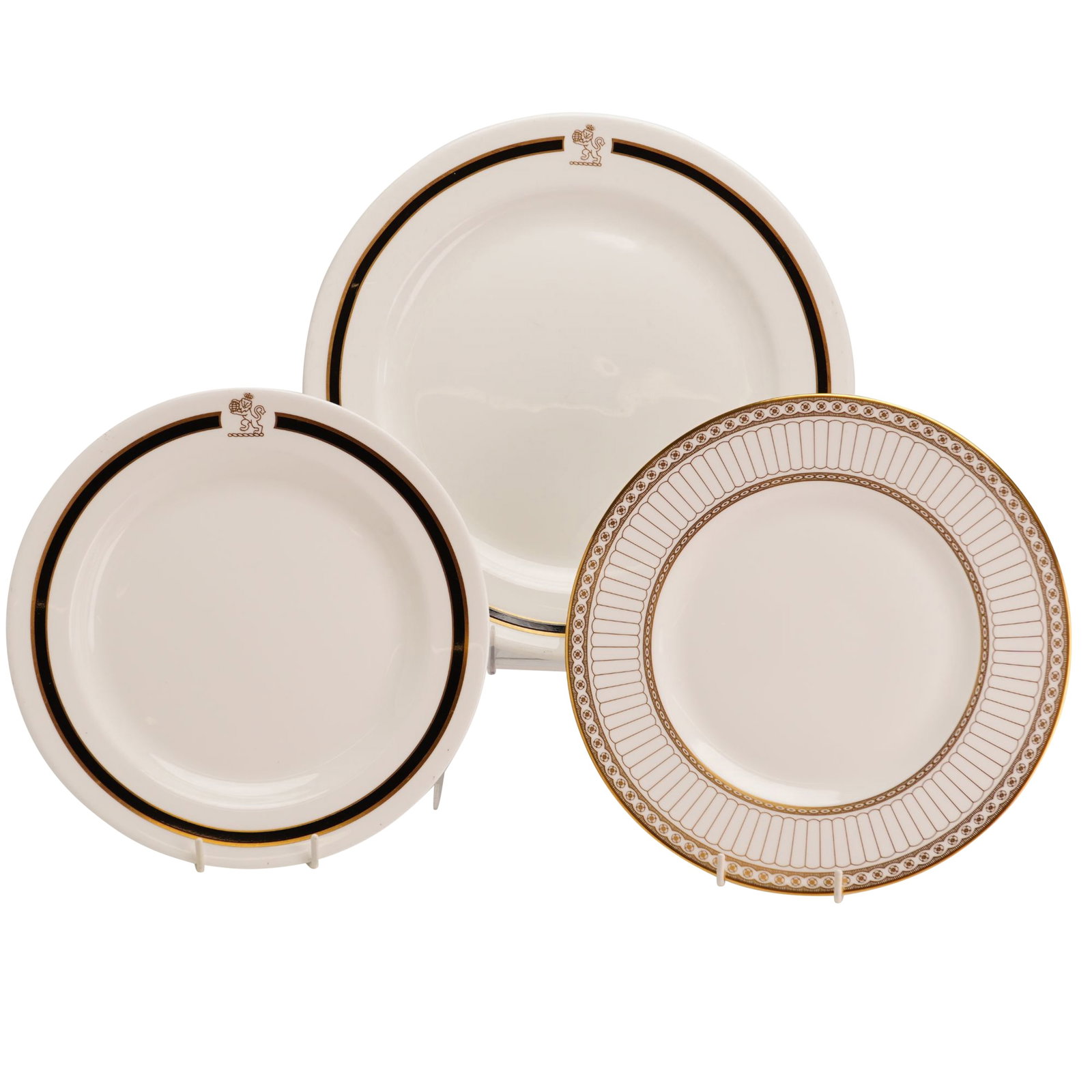 Three Wedgwood Porcelain Plates Including Metallised and Colonnade Gold: The group includes two plates featuring the Metallised design, characterized by a wide black band on the rim edged in gold. At the top of each of these plates is a brown transfer-printed crest depicti
