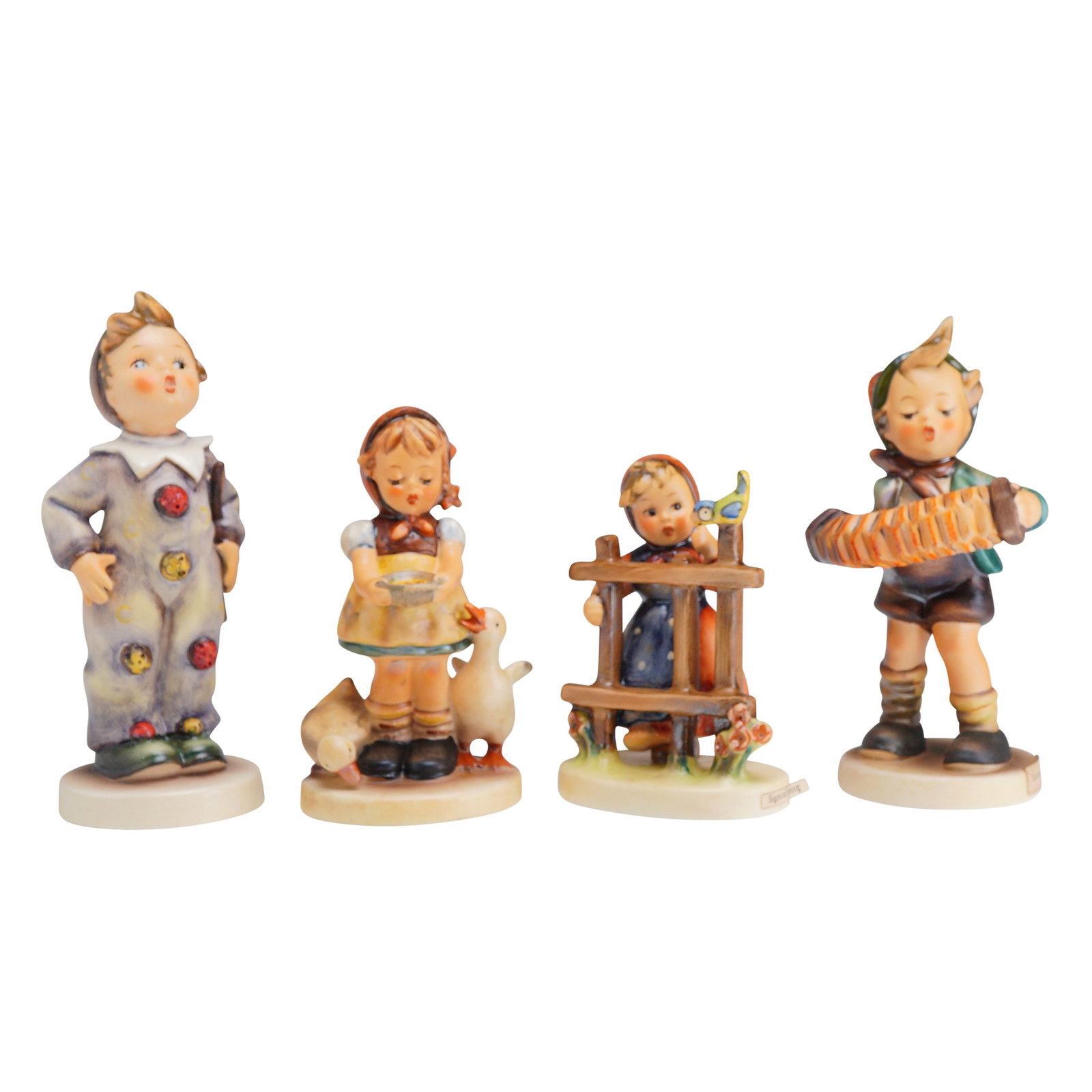 4pc Goebel Hummel Figurines: This collection features four hand-painted ceramic figurines from the M.I. Hummel series, manufactured by Goebel in West Germany. The set includes Carnival (model 328) depicting a young boy in a pierr