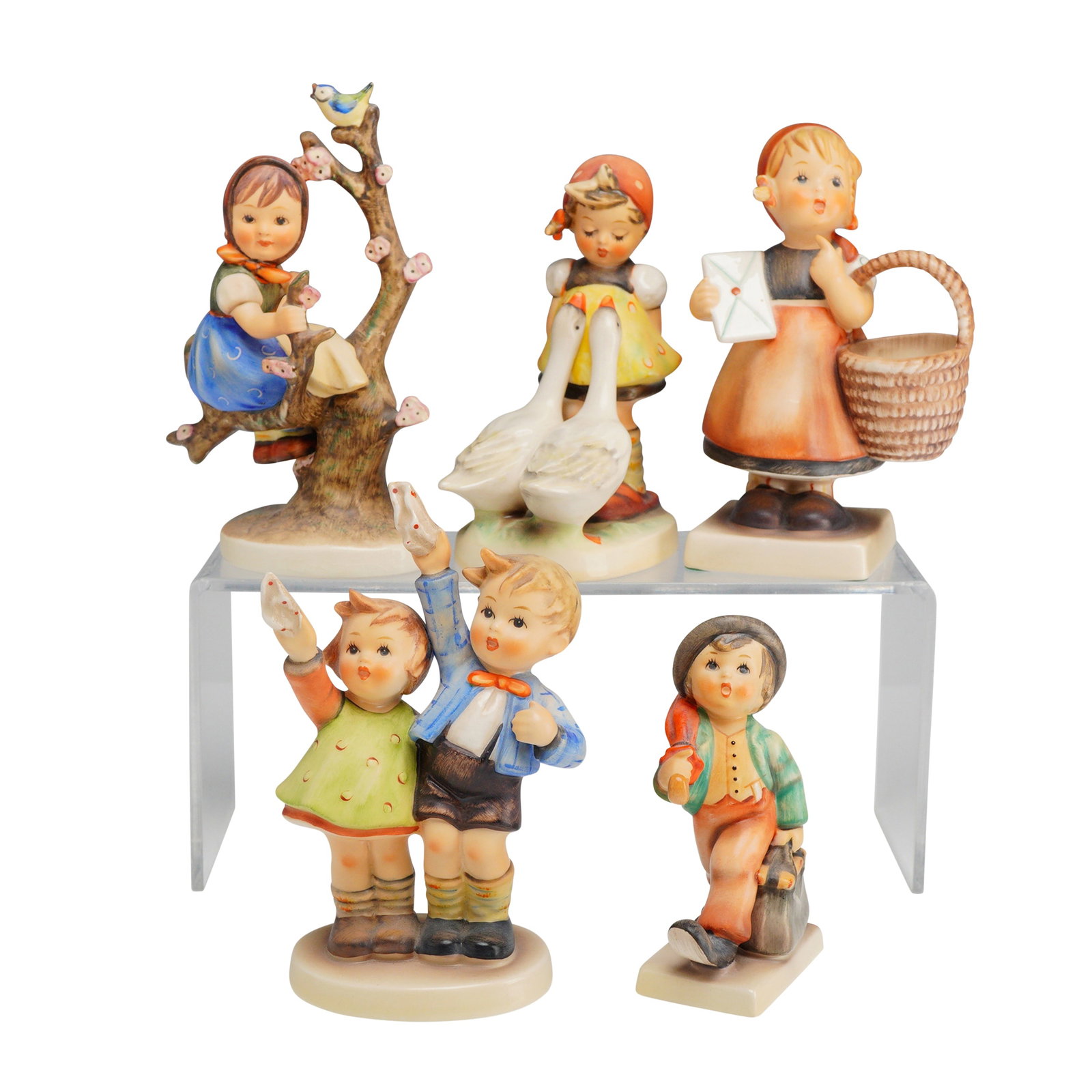 Five Piece Collection of Goebel M.I. Hummel Porcelain Figurines: This collection of hand-painted porcelain figurines was produced by the Goebel porcelain factory and is based on the drawings of Sister Maria Innocentia Hummel. The group includes various patterns suc