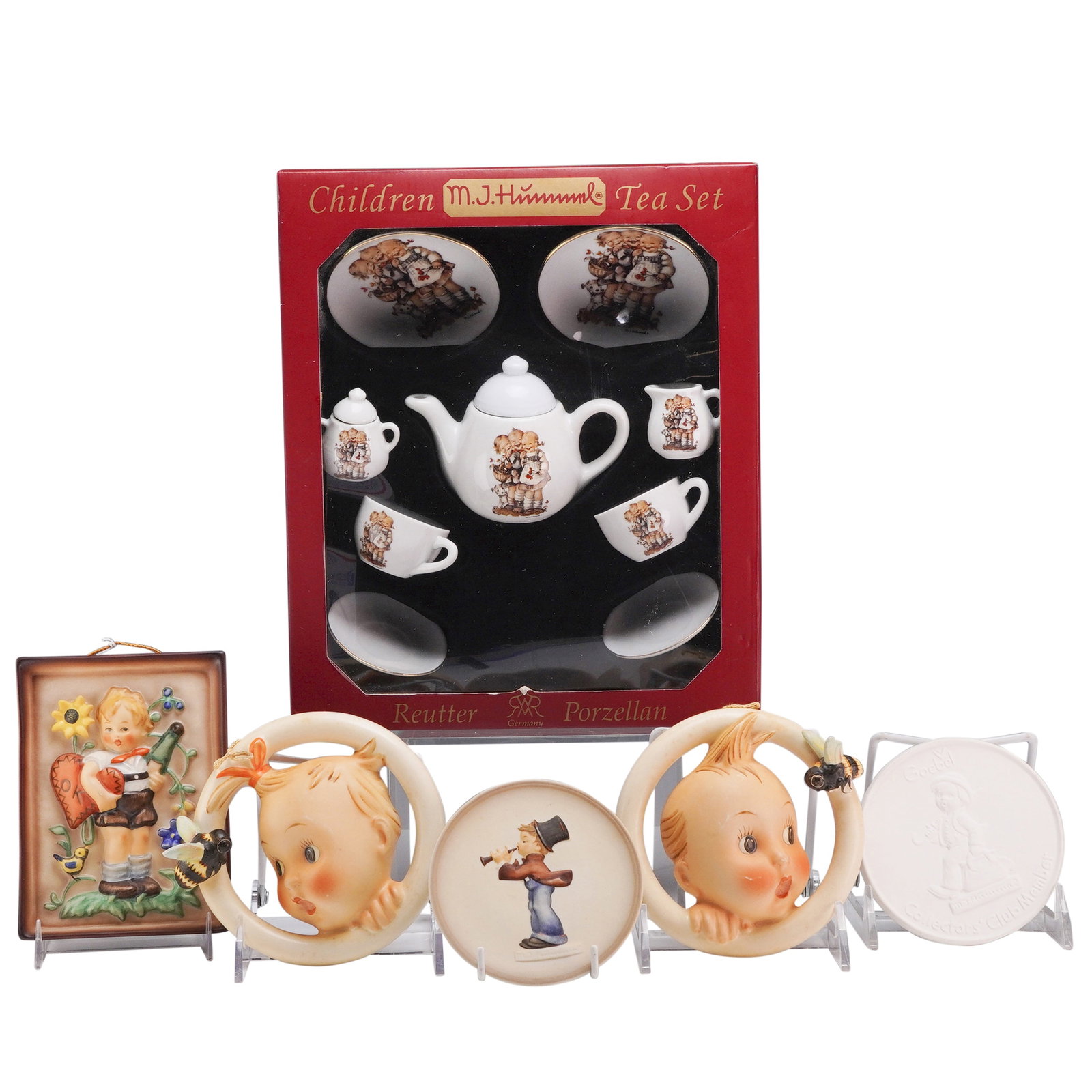 6pc Collection of Goebel M.J. Hummel Wall Plaques and Miniature Tea Set: This collection features six M.J. Hummel themed ceramic items manufactured by Goebel and Reutter Porzellan. The lot includes a boxed miniature tea set and five individual decorative pieces consisting 