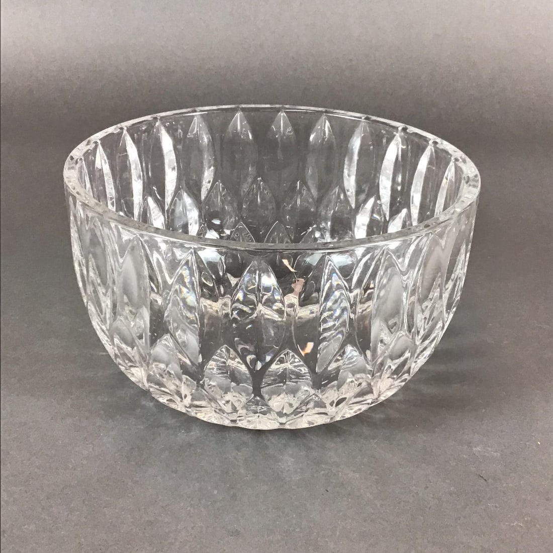 Crystal Bowl with Leaf Design: This deep, circular bowl is constructed of heavy, high-clarity colorless lead crystal. The exterior is decorated with a repeating pattern of tiered, large-scale almond or leaf cuts. These deep facets 