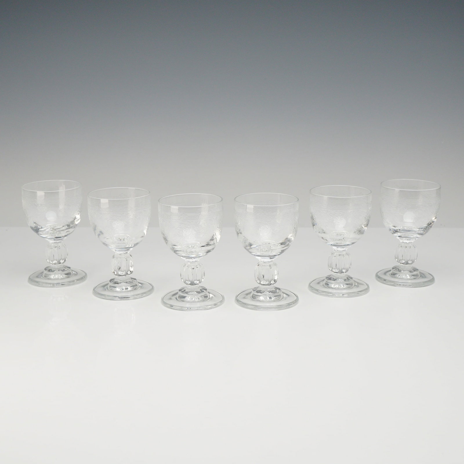 6pc Floral Etched Cordial Glasses: A set of six stemmed cordial or liqueur glasses manufactured from lead crystal. The bowls are decorated with fine etched ornamentation featuring a narrow geometric band of cross-hatching at the rim an