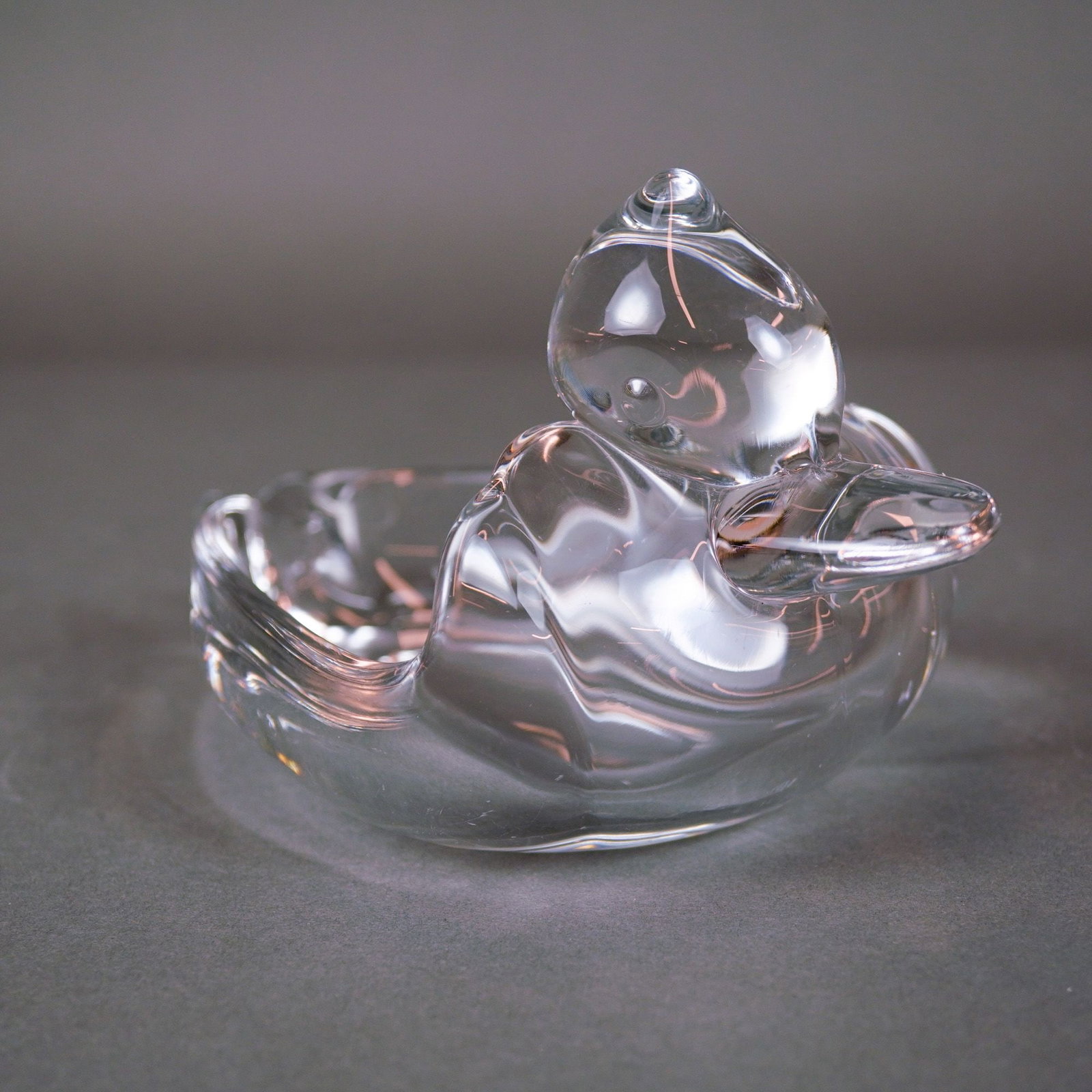 Orrefors, Sculpted, Crystal Duck Ash Tray: This Crystal Duck Ash Tray is a mid-century modern clear crystal piece produced by Orrefors of Sweden. The item is hand-formed and sculpted from a single gather of molten lead crystal, featuring a sty