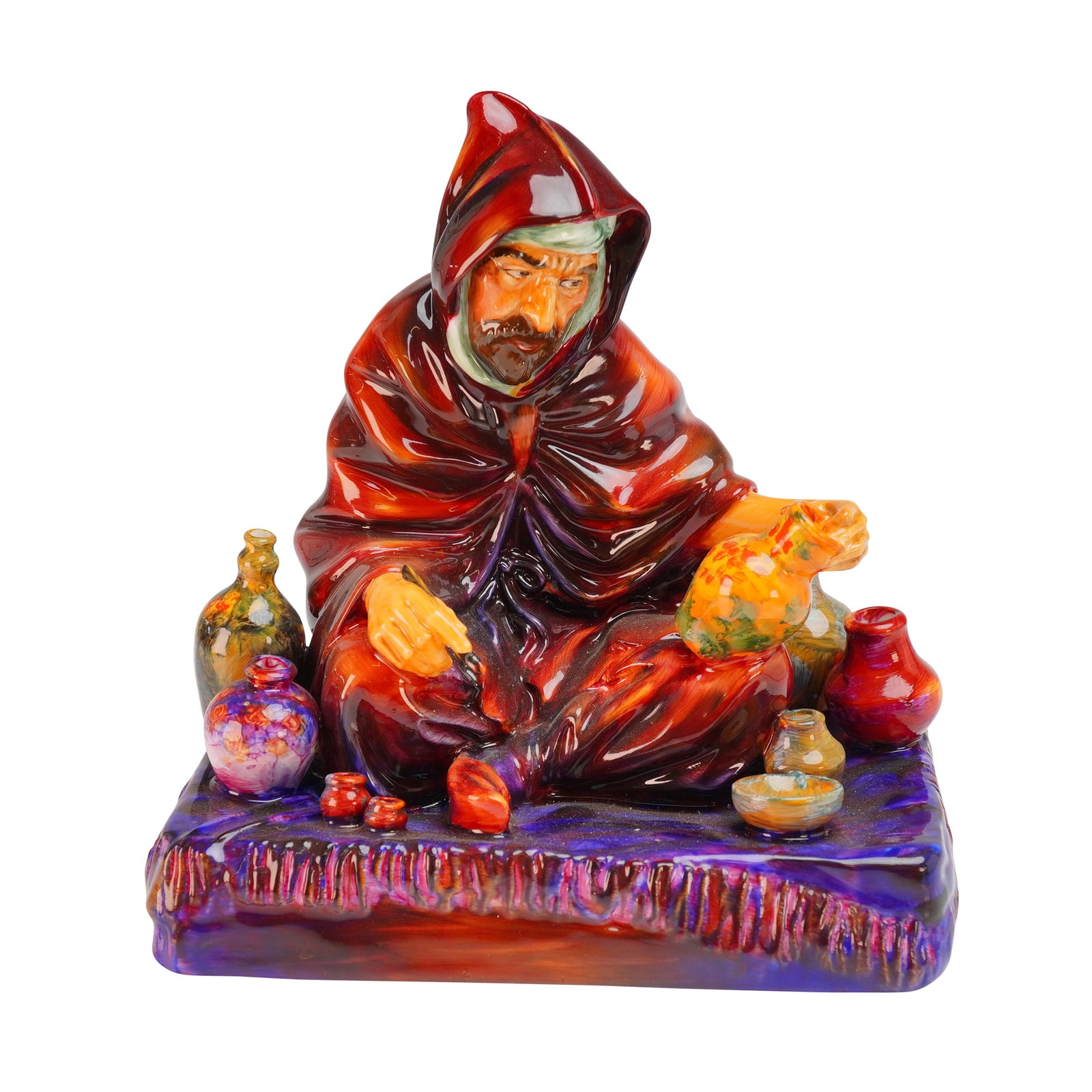 Royal Doulton Figurine The Potter HN1493: A Royal Doulton bone china figurine titled The Potter, model HN1493. The piece depicts a seated man wearing a hooded robe in deep red tones, shown painting a yellow jar. The figure is surrounded by va