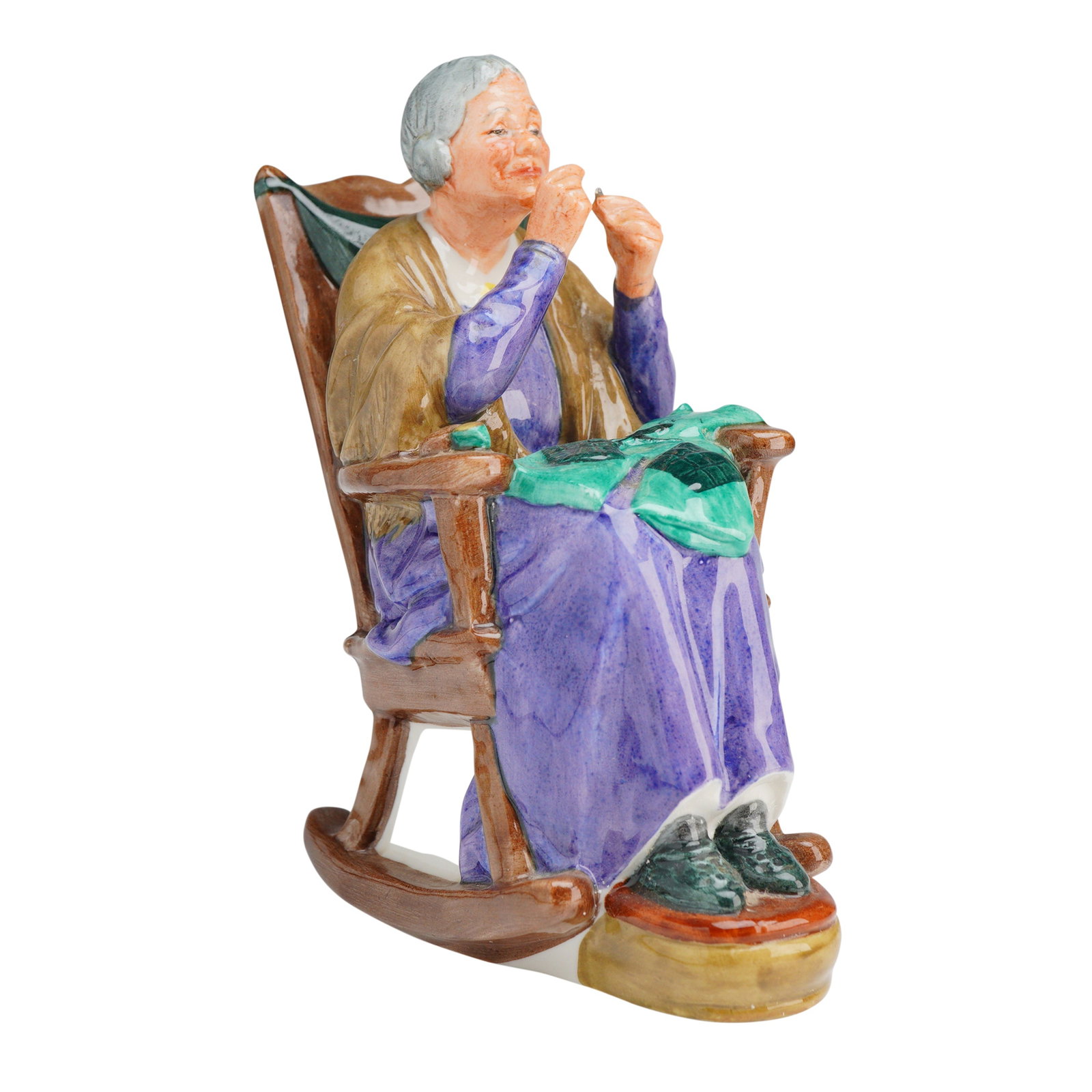 Royal Doulton Porcelain Figurine A Stitch in Time HN2352: A Royal Doulton Porcelain Figurine, A stitch in time (HN2352), depicting an elderly woman sewing in a purple and tan dress seated in a brown rocking chair, marked COPR 1965 and H.N. 2352 on the base. 
