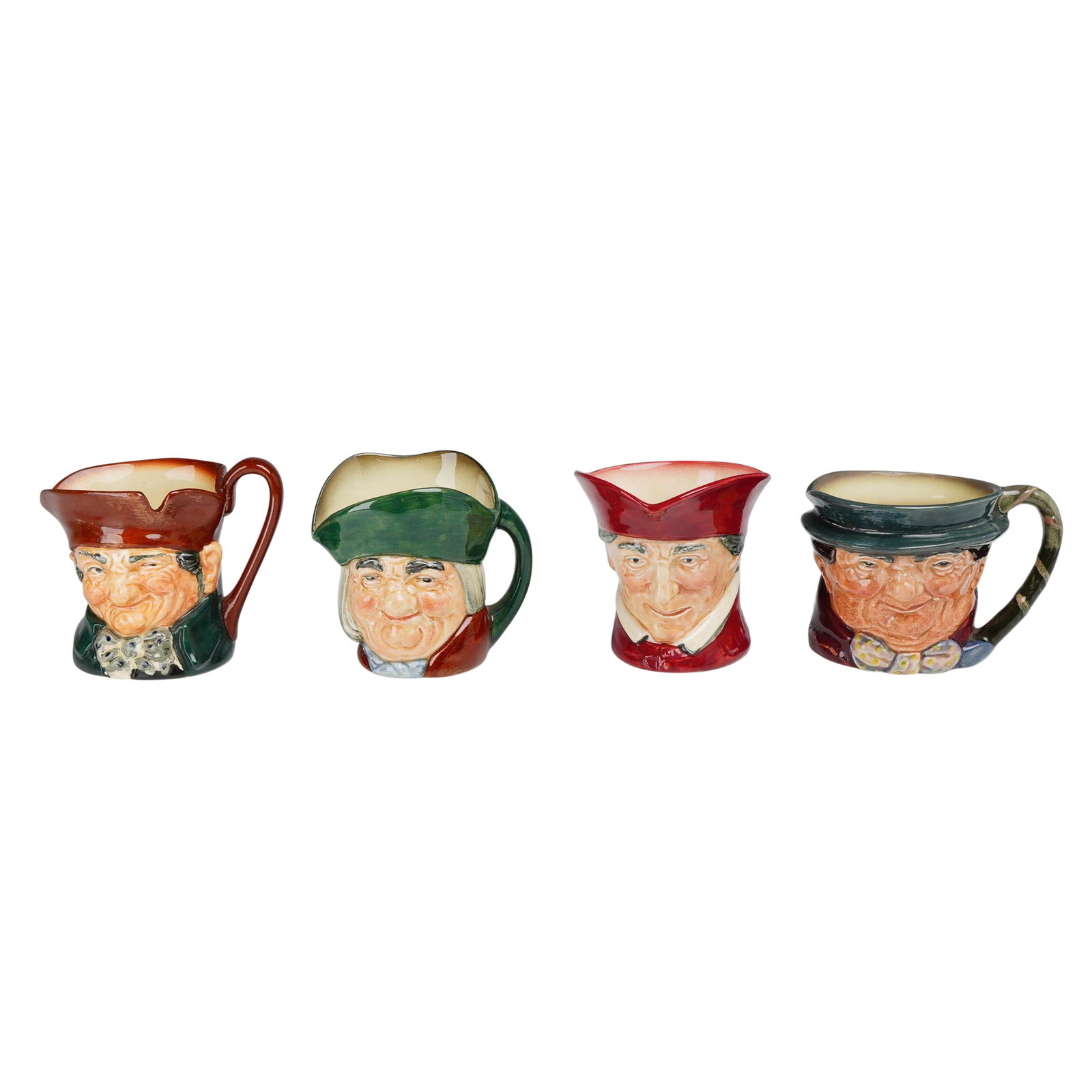 4pc Royal Doulton Small Ceramic Character Jugs: This lot consists of four Royal Doulton earthenware character jugs featuring various literary and historical figures. Each jug is a head-and-shoulders depiction with a high-gloss glaze finish. The cha