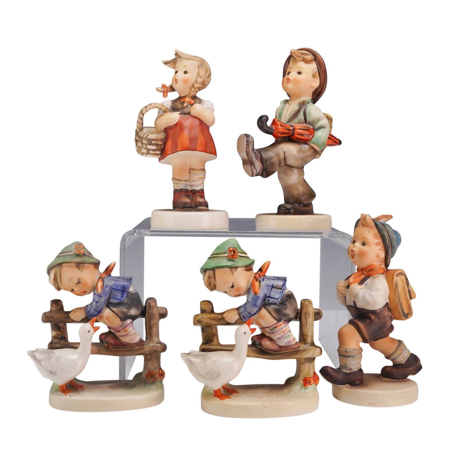 5pc Goebel Hummel Porcelain Figurines: A collection of 5pc Goebel M.I. Hummel hand-painted porcelain figurines manufactured in West Germany. This assortment features traditional designs by Sister Maria Innocentia Hummel, including two Barn