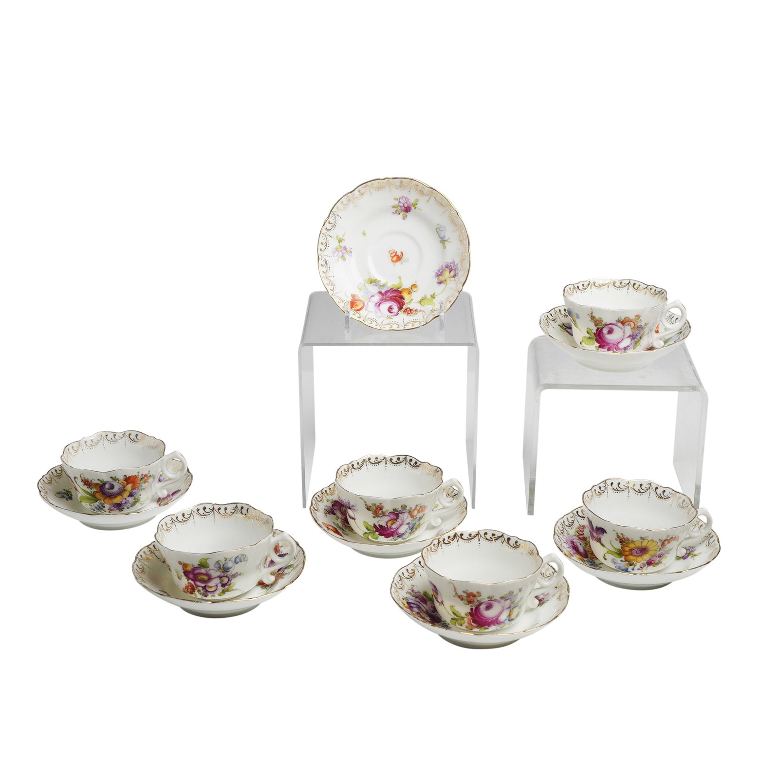 13pc Schlesische Porzellanfabrik Louis Lovinsohn and P. Donath Porcelain Tea Set: This 13 piece china set is crafted from hard-paste porcelain. The set consists of six cups and seven saucers featuring scalloped and lobed rims. The cups are designed with loop handles that include a 