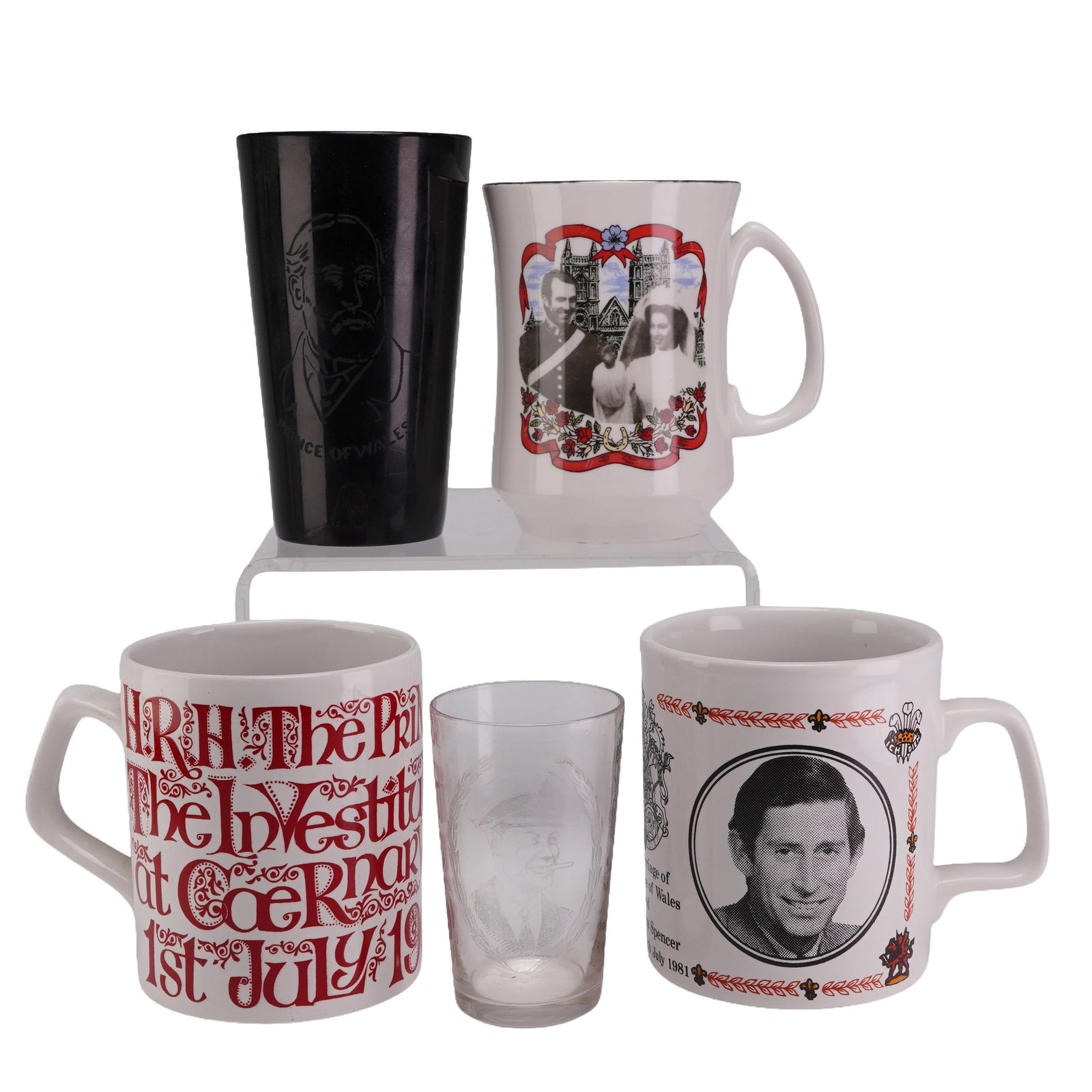 Collection of Five British Royal Commemorative Tableware: A collection of British Royal commemorative tableware including ceramic mugs and glassware. The collection features a white ironstone mug commemorating the 1981 marriage of the Prince of Wales and Lad